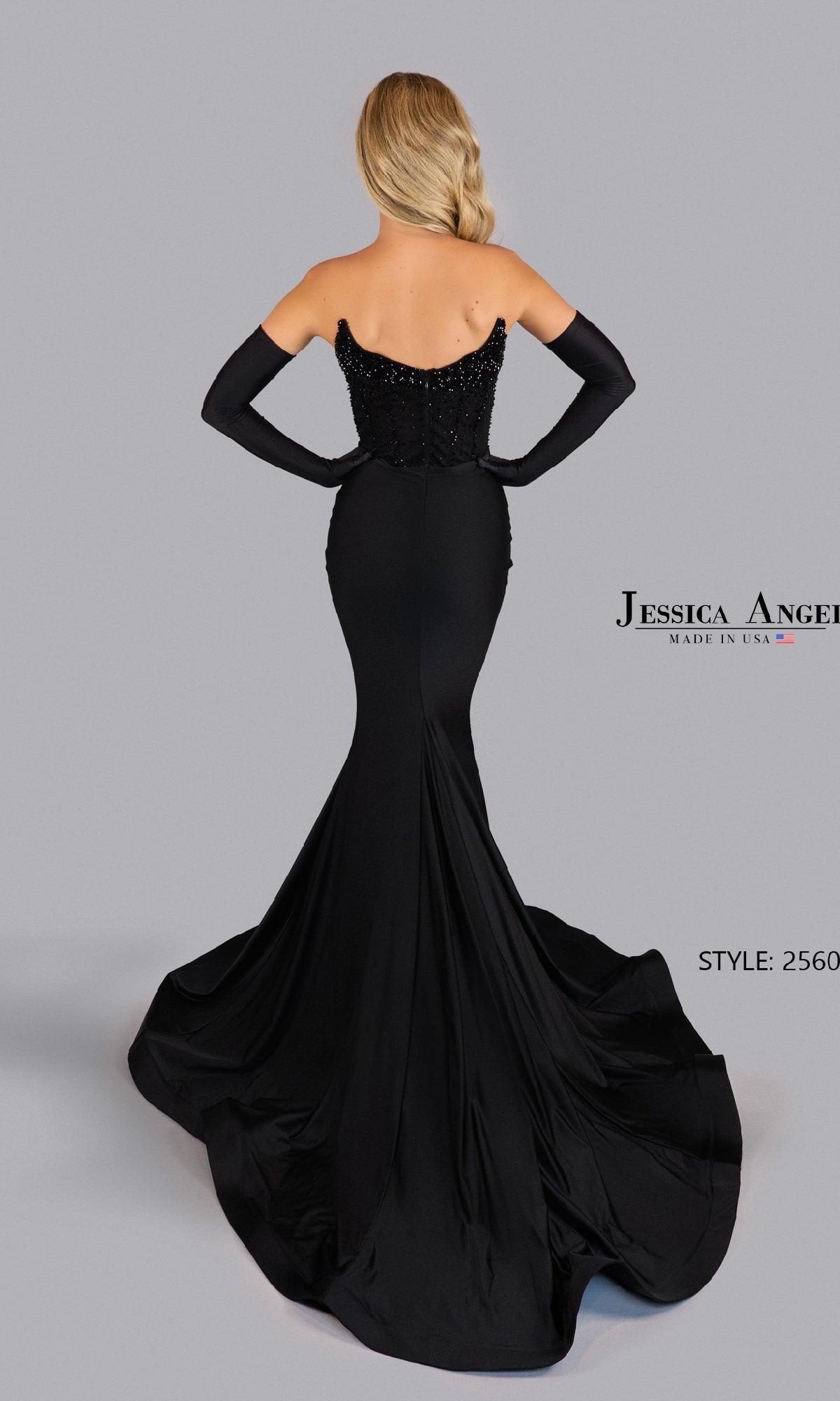 A woman in the Jessica Angel 2560 strapless prom dress with gloves and a fitted, corset-style bodice stands facing away from the camera.