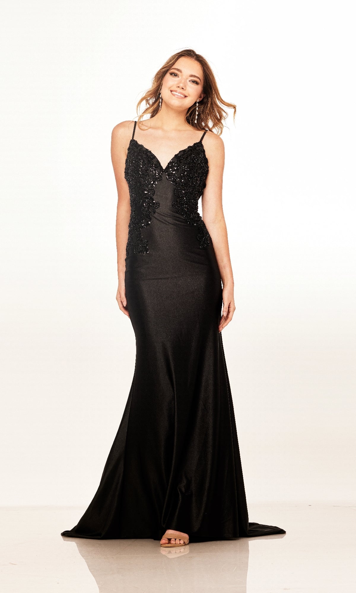 A woman smiles at the camera against a plain white background, wearing the Cecilia Couture 2602 long prom dress, a form-fitting style with thin straps and floral embellishments.