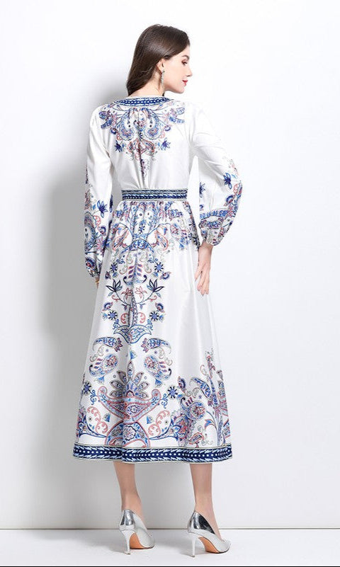 Woman in a Long-Sleeve Paisley-Print Casual Maxi Wrap Dress featuring blue and red patterns, paired with silver high heels, facing away from the camera against a plain white background.