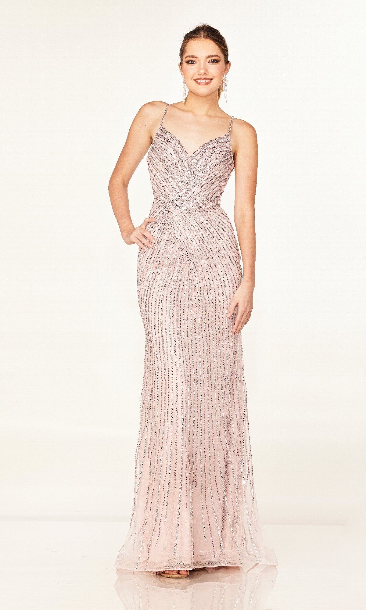 A woman models the Cecilia Couture 2616 long prom dress, featuring light pink sparkly fabric, thin straps, a v-neckline, and vertical sequin details against a plain background.