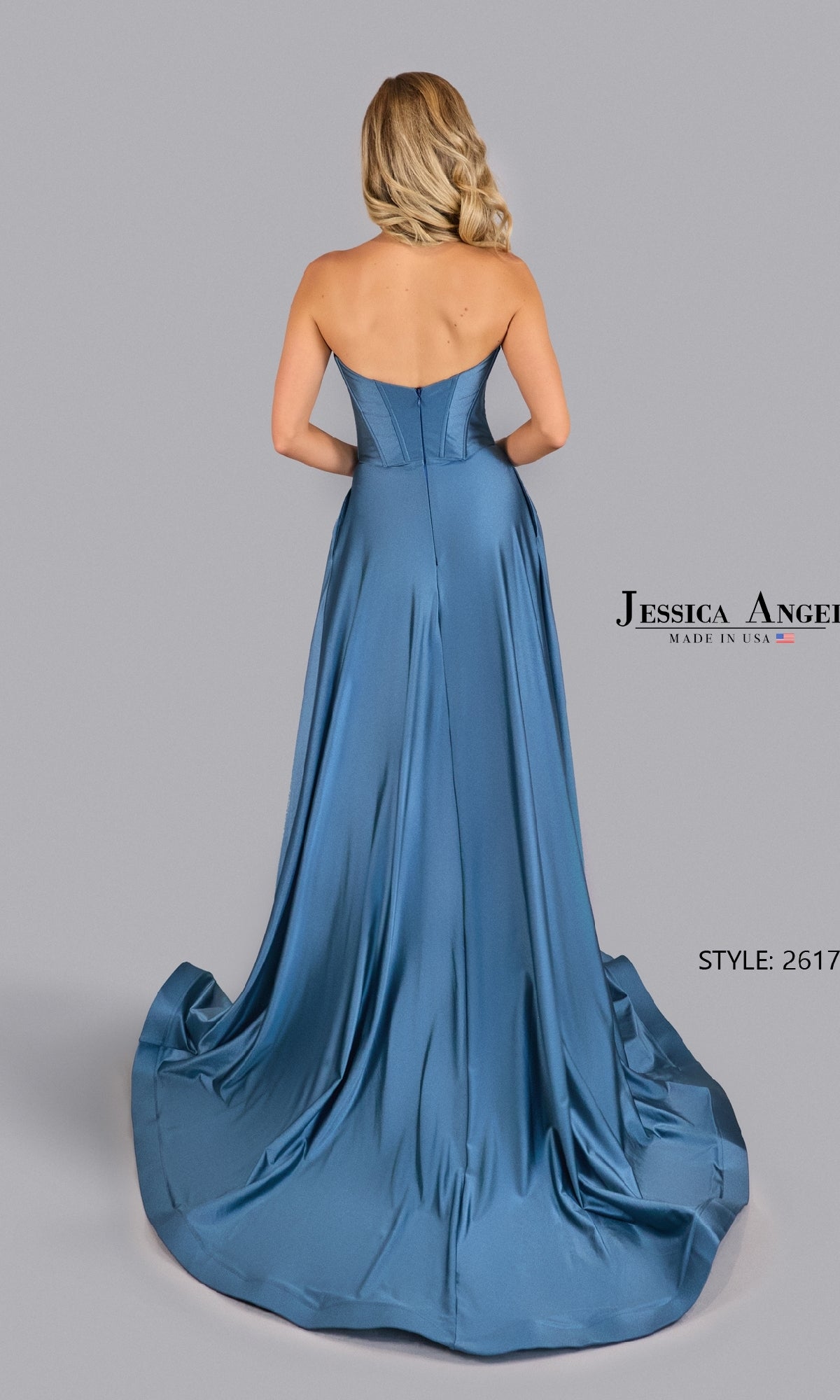 A woman models the Strapless V-Neck Prom Gown: Jessica Angel 2617, facing away to showcase its fitted bodice and flowing, floor-length blue satin skirt—an elegant choice for formal evening events.