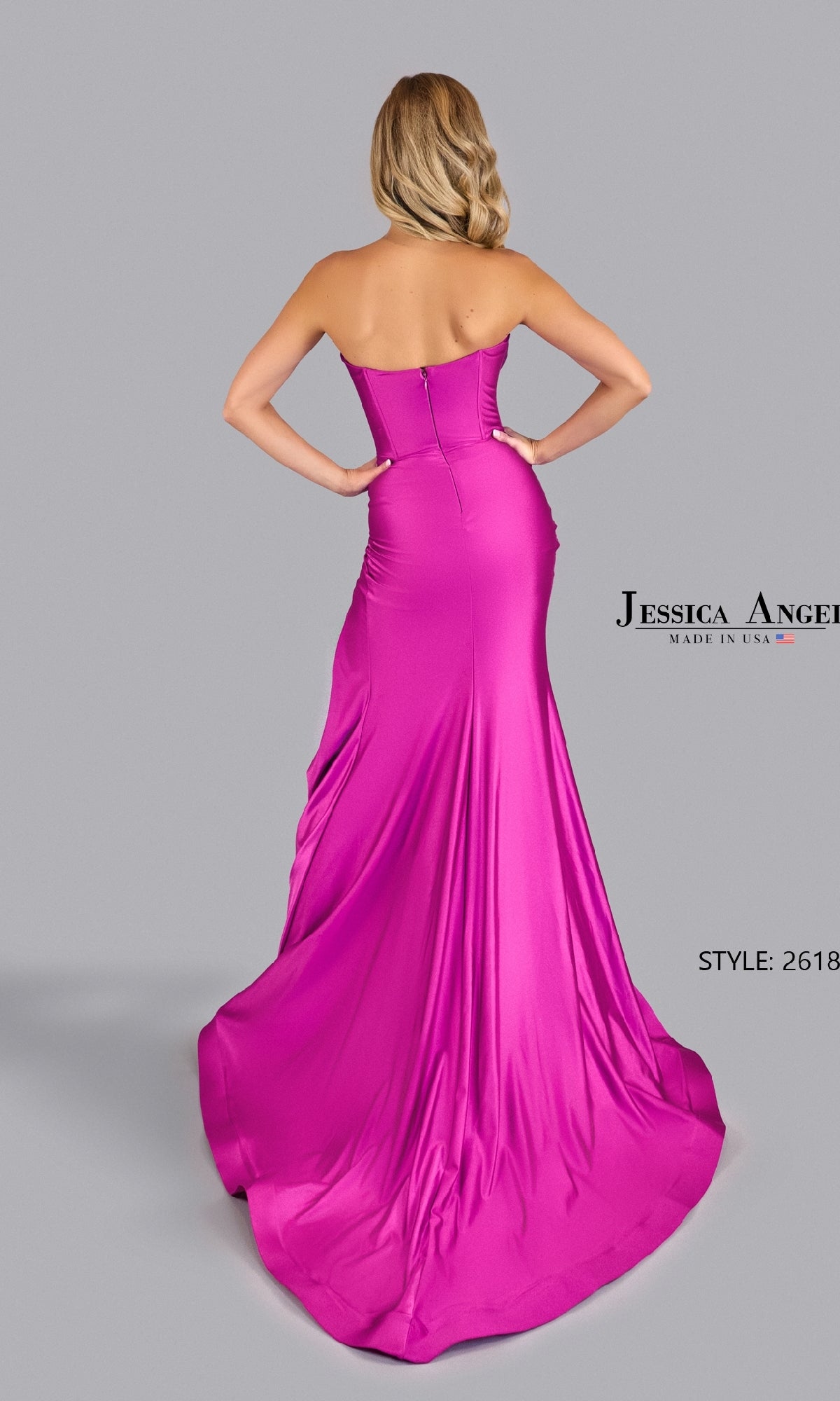 A woman stands facing away, showcasing the elegant back of the strapless, floor-length bright pink Jessica Angel 2618 Front-Twist Long Prom Gown against a plain gray background.