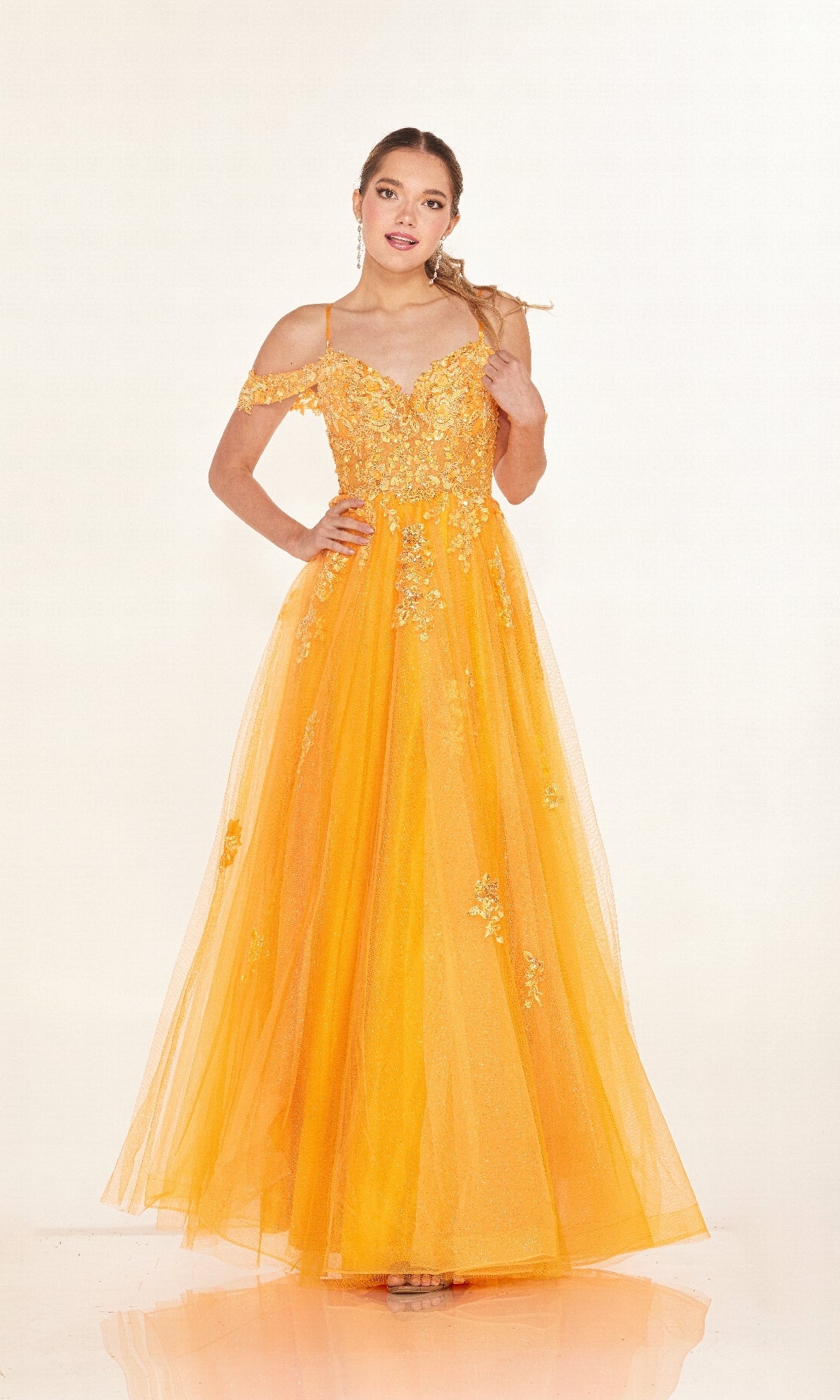 A woman wears the Cecilia Couture 2618 long prom dress with an off-the-shoulder neckline, tulle overlay, and delicate floral embroidery, posing against a plain light background.