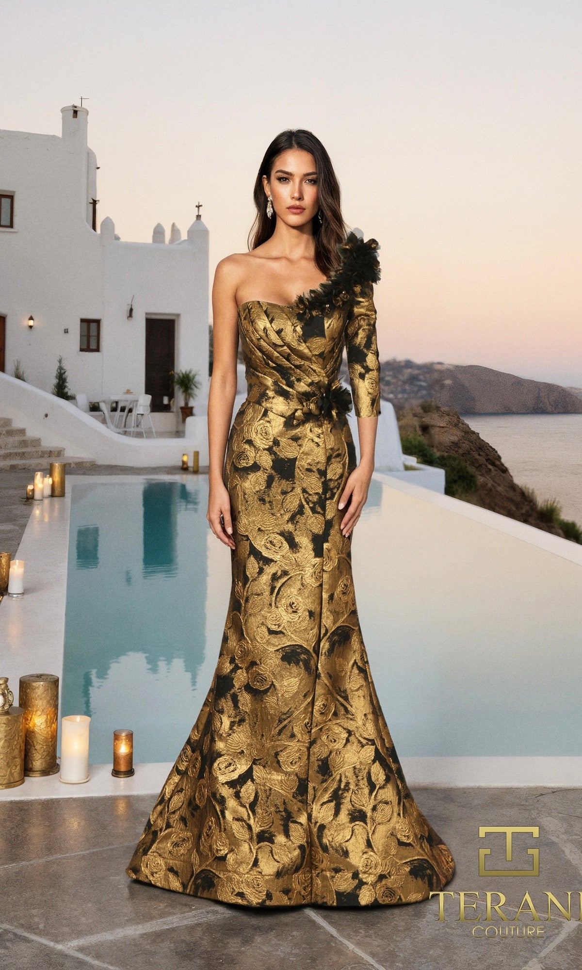 A woman in the Terani 261E6275 Long Formal Dress in black gold stands by a pool, with white buildings and a coastal view in the background.