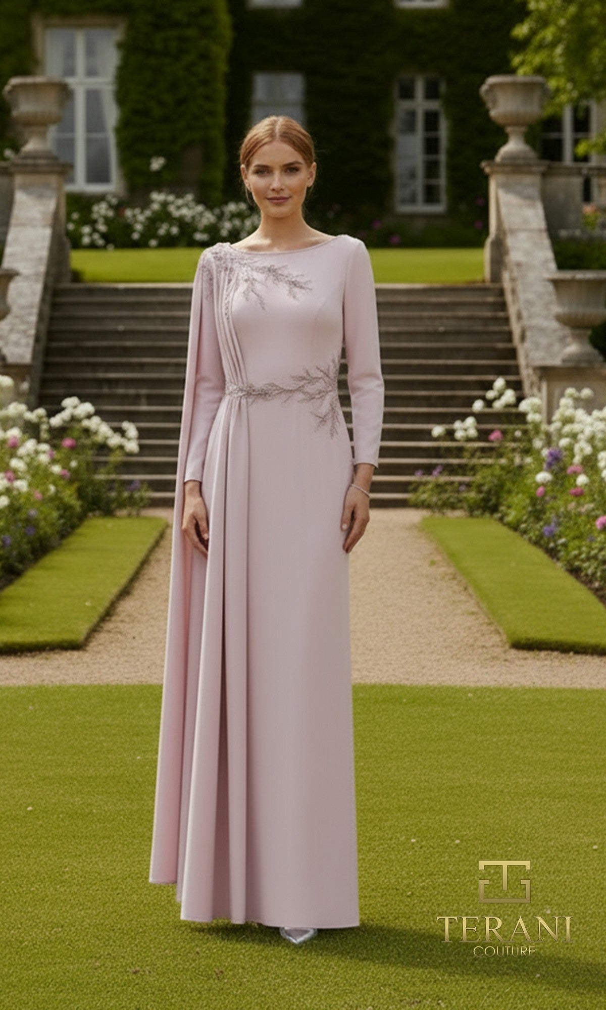 A woman stands outdoors before steps and greenery, wearing the Terani 261M6465 long formal dress in Pink Tulip with silver embroidery and a cape. An elegant choice for mother-of-the-bride, with the Terani Couture logo at the bottom right.