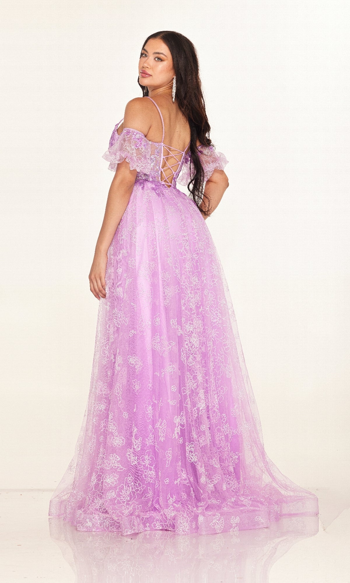 Woman poses against a plain background wearing the Cecilia Couture 2620, a long prom dress featuring off-the-shoulder lace details and a sheer corset bodice.