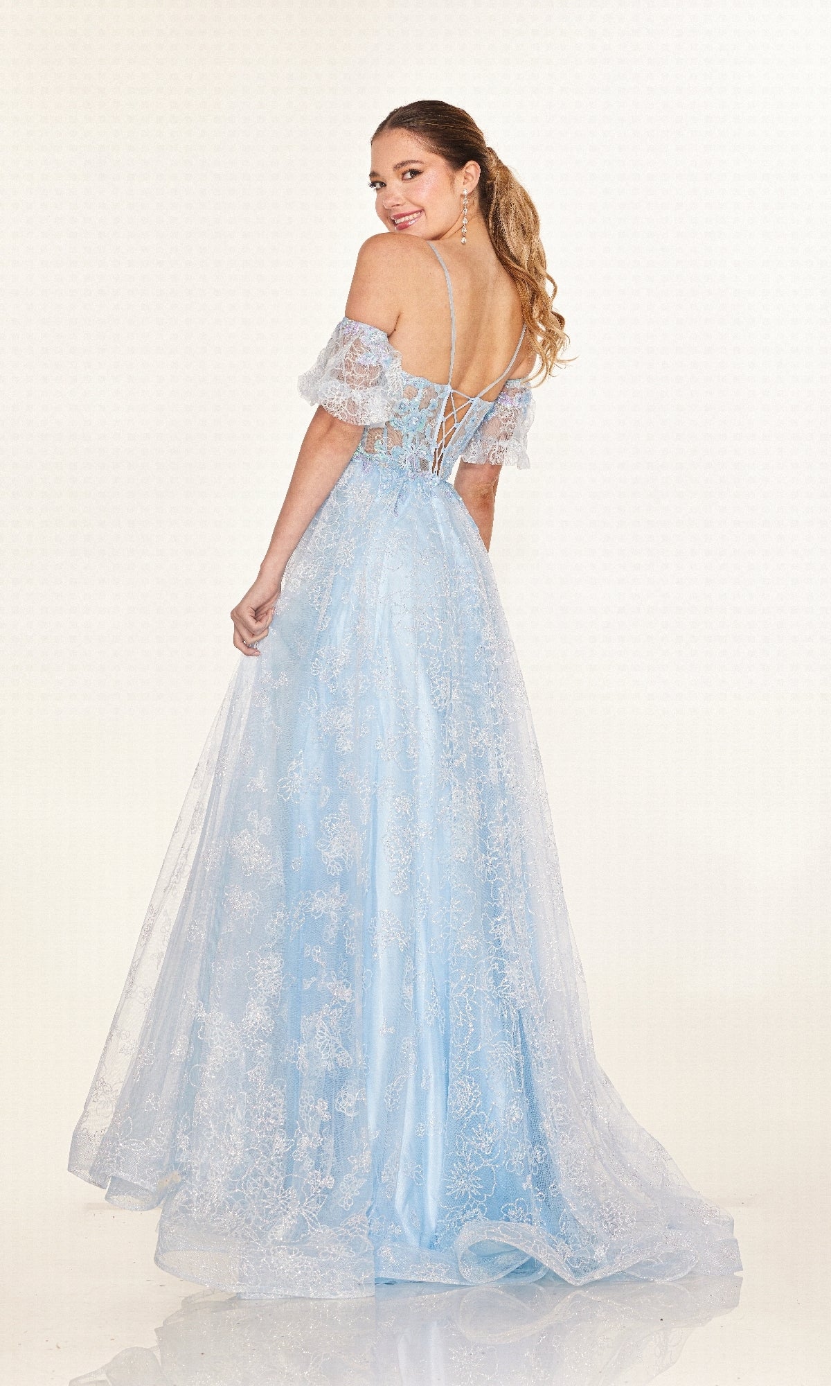 A woman models the Long Prom Dress: Cecilia Couture 2620, featuring a pastel color, sheer corset bodice with lace details, and lace-up back, as she faces away from the camera.