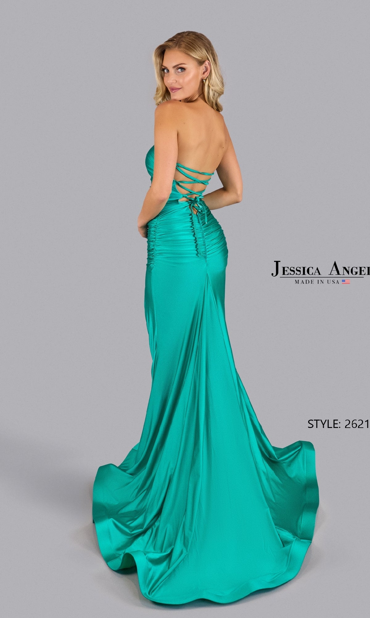 A woman models the Lace-Up Strapless Prom Dress: Jessica Angel 2621, a turquoise, floor-length gown with a lace-up back, standing before a plain gray background.