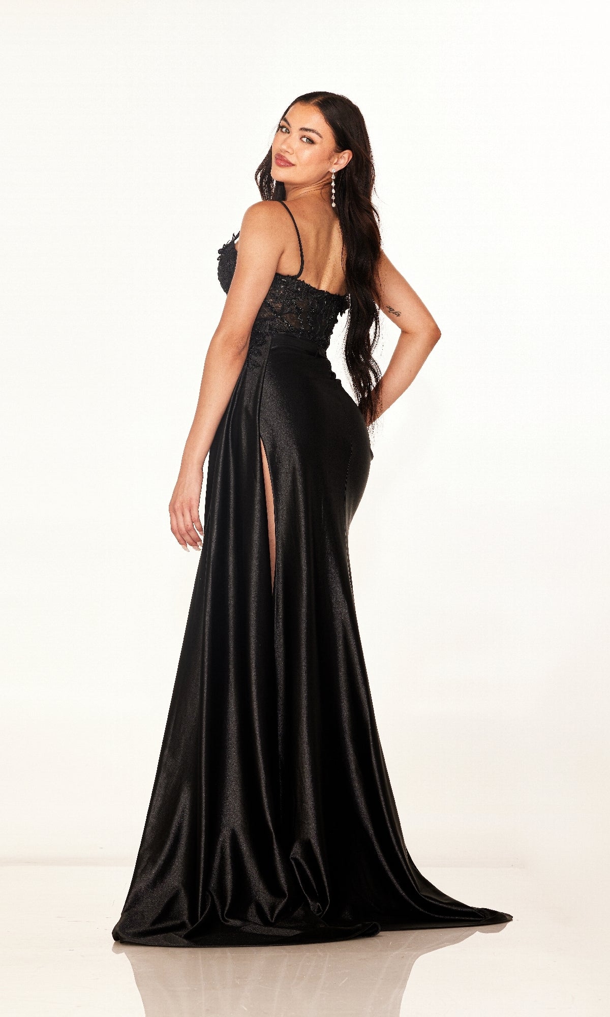 A woman models the Cecilia Couture 2627 long prom dress, featuring a high leg slit and sleeveless design, as she poses against a plain white background looking over her shoulder.