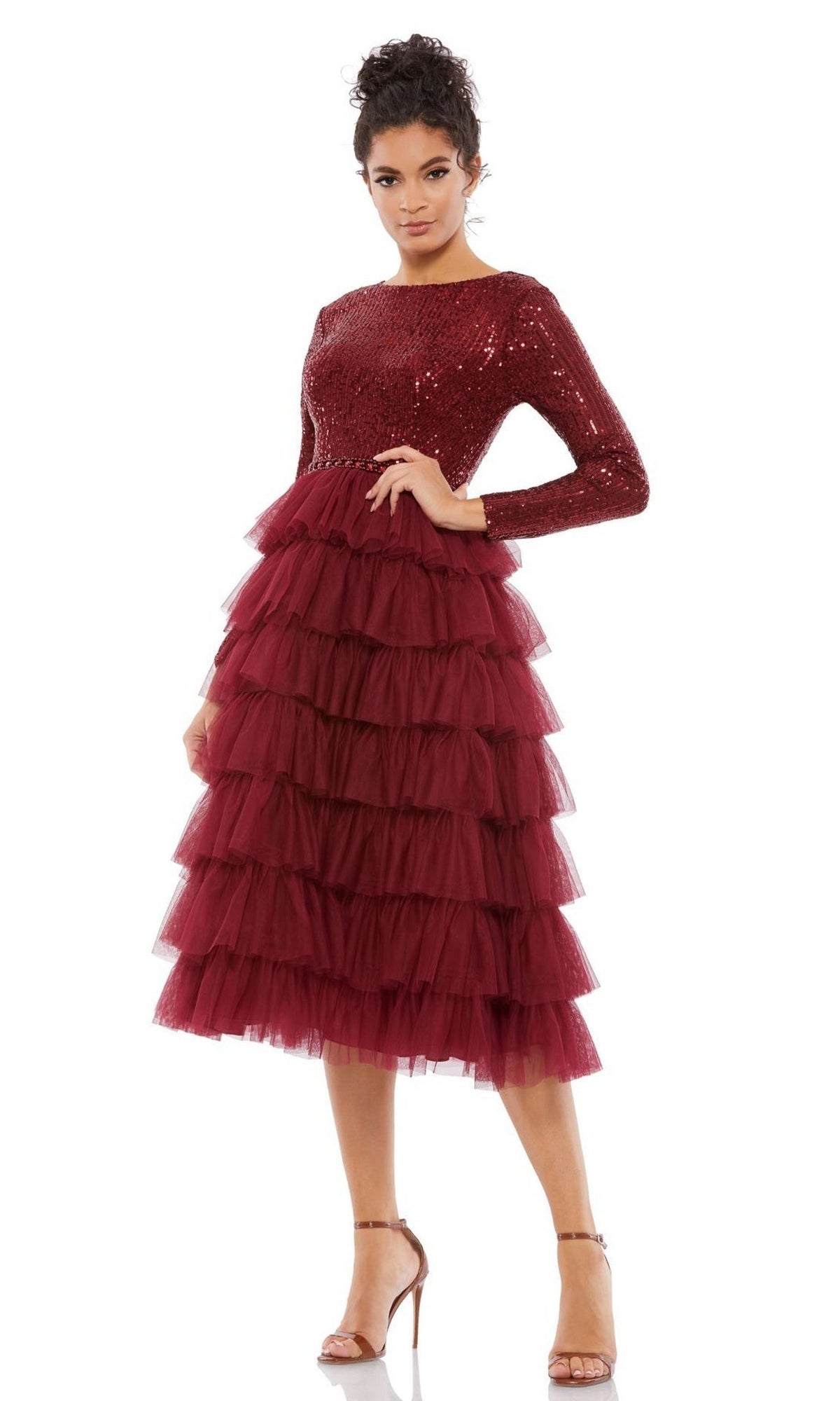 A woman models the Mac Duggal 26299 Knee-Length Wedding Guest Dress, featuring a sequined burgundy top and tiered tulle skirt, paired with strappy heeled sandals against a white background.