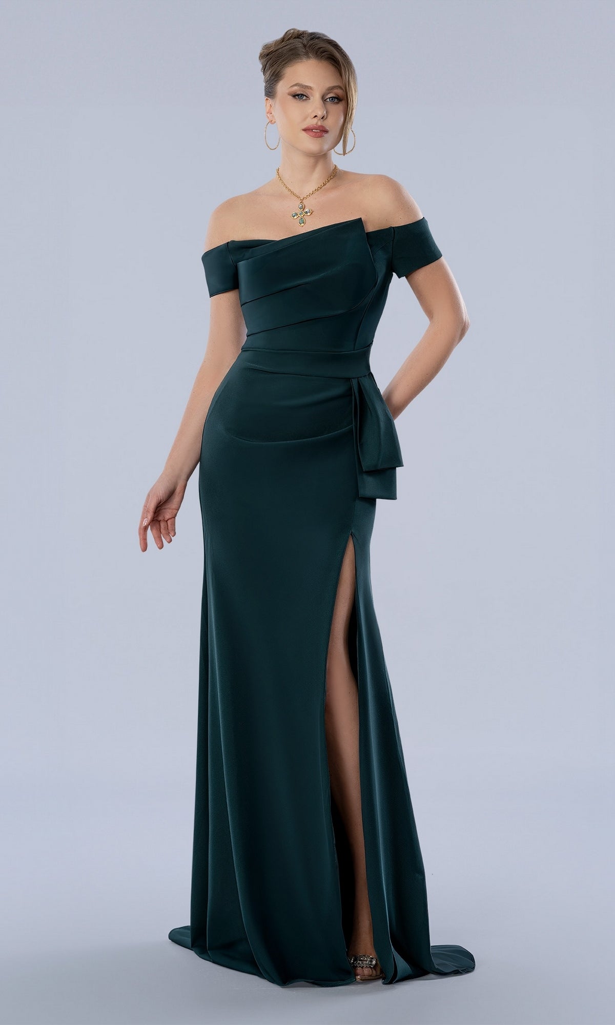 Emerald green Stella Couture 26371 off-the-shoulder evening gown featuring a waist drape and a high side slit.