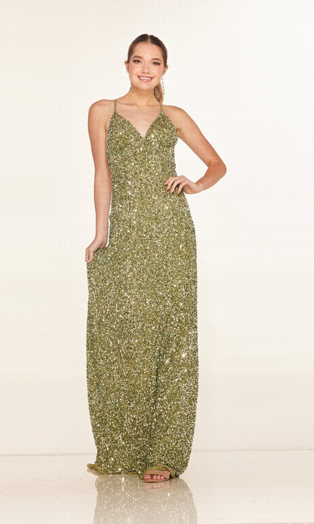 A woman poses against a plain light background in the Cecilia Couture 2640, a floor-length gold sequin prom dress featuring spaghetti straps and a v-neckline.