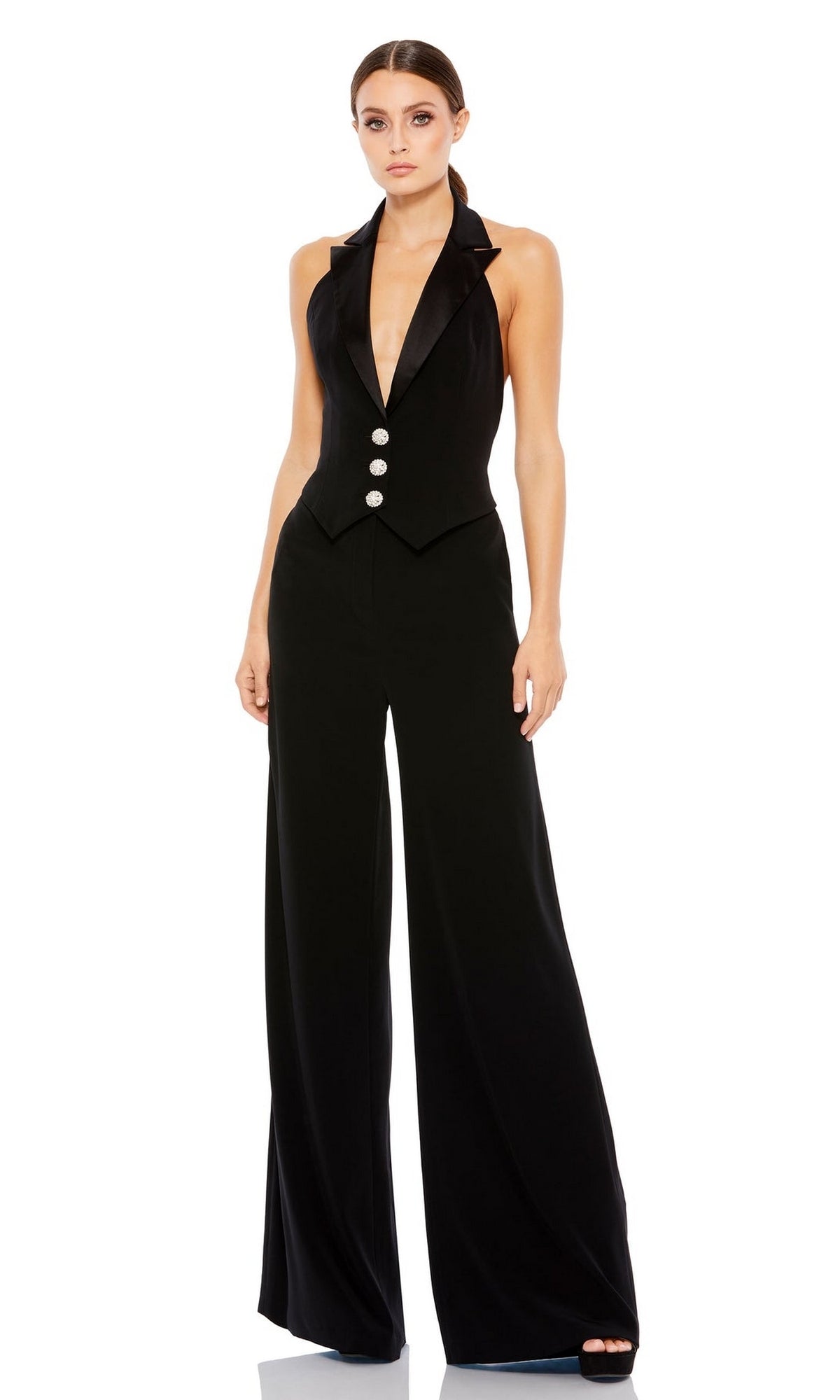 Woman wearing the Long Formal Jumpsuit 2643 by Mac Duggal, a sleeveless black halter jumpsuit with a deep V-neck, three front buttons, and wide-leg pants.