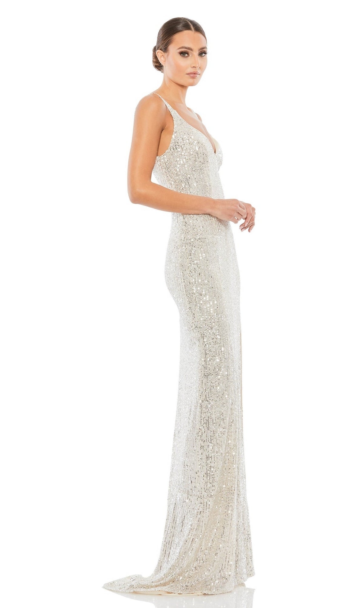 A woman stands in profile against a white background wearing the Mac Duggal 26443 Sexy Long Sequin Formal Dress, a floor-length silver gown with thin straps.