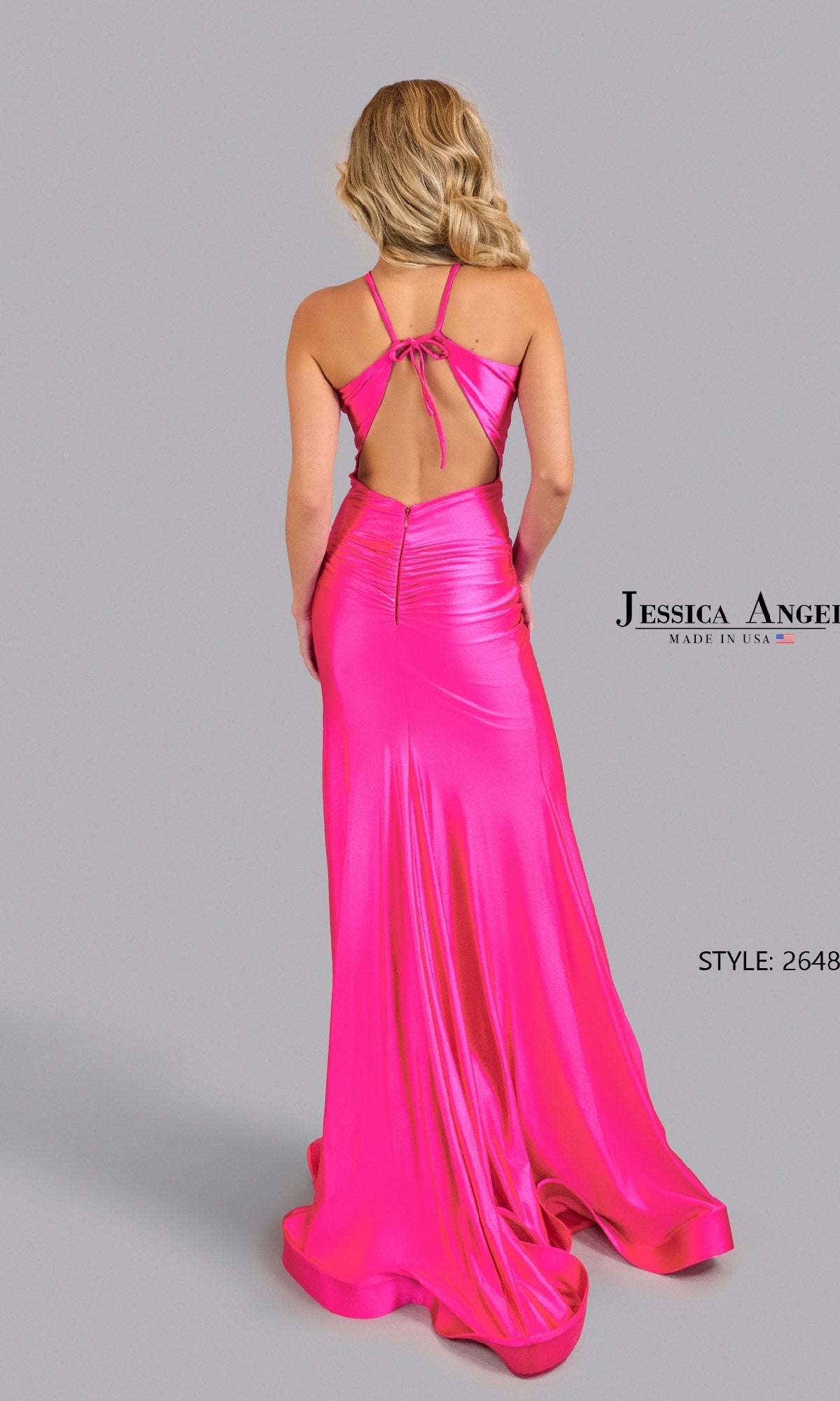 A blonde woman wears the Jessica Angel 2648 Cut-Out Sexy Long Prom Dress in bright pink, featuring a satin halter neckline, open back, and floor-length train, standing against a plain gray background.