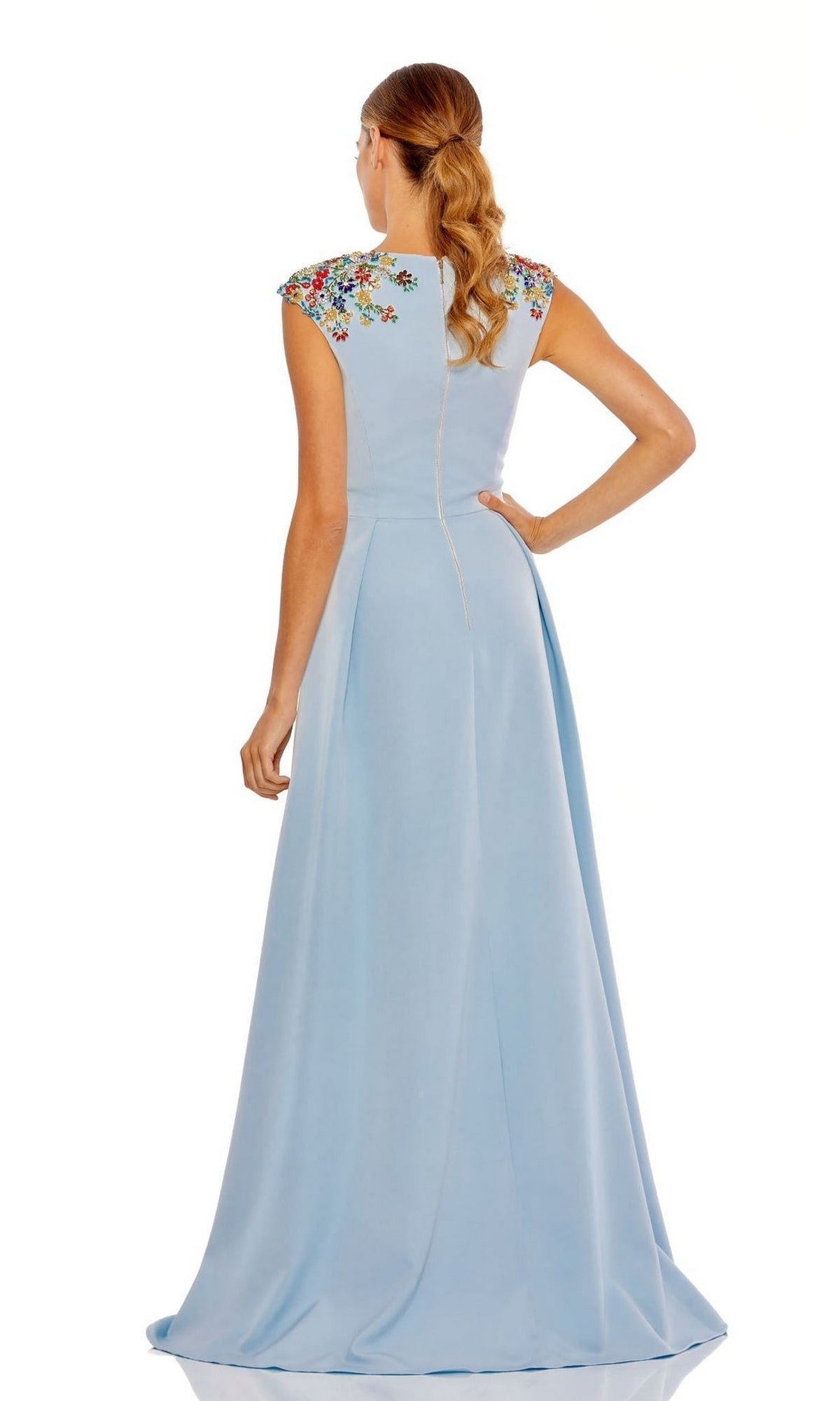 A woman faces away from the camera in the Cap-Sleeve Long Formal Dress: Mac Duggal 26540, a light blue A-line gown with floral embroidery on the shoulders.