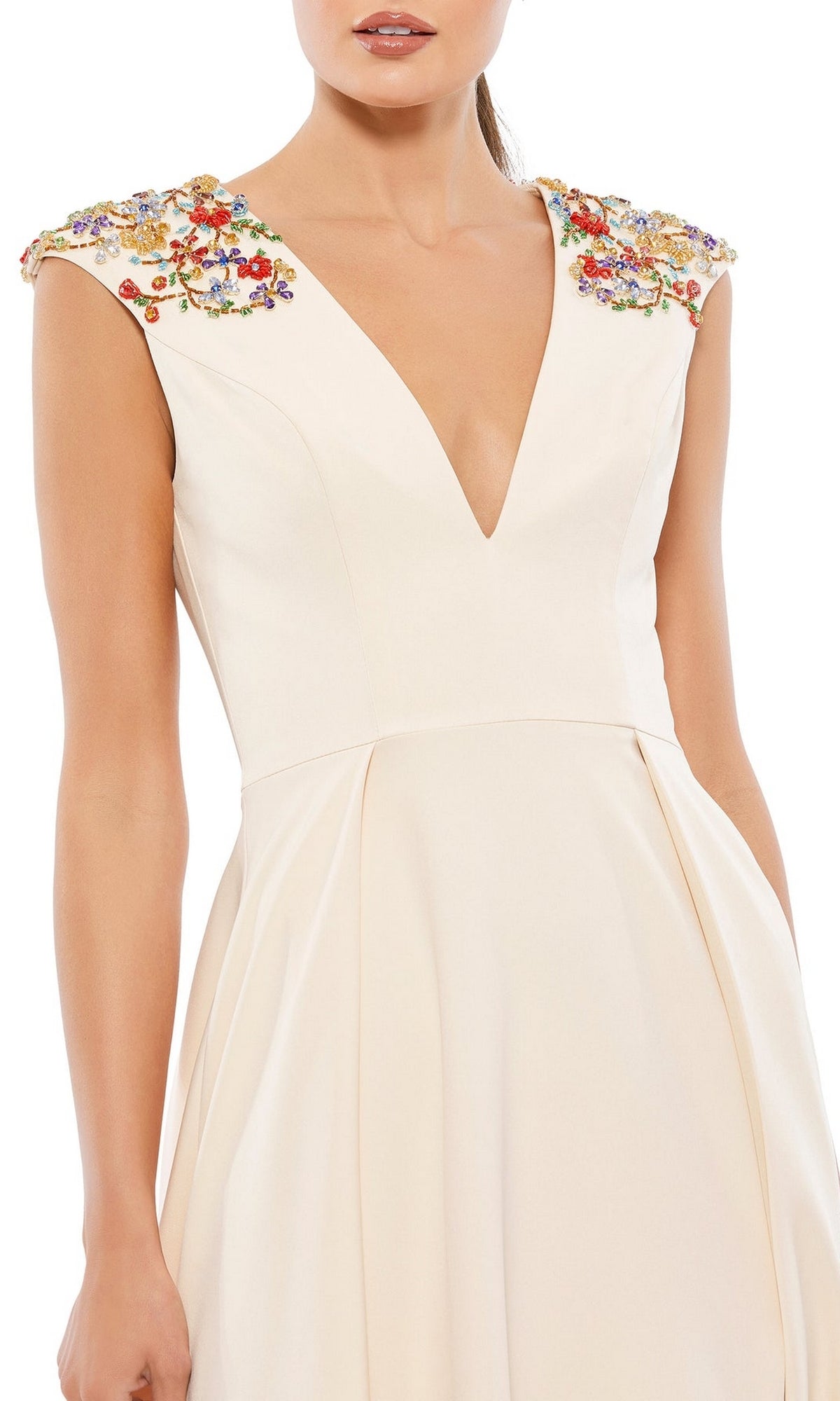 A woman wears the Cap-Sleeve Long Formal Dress: Mac Duggal 26540, a cream-colored A-line gown with a deep V-neck and colorful floral embroidery on the shoulders.