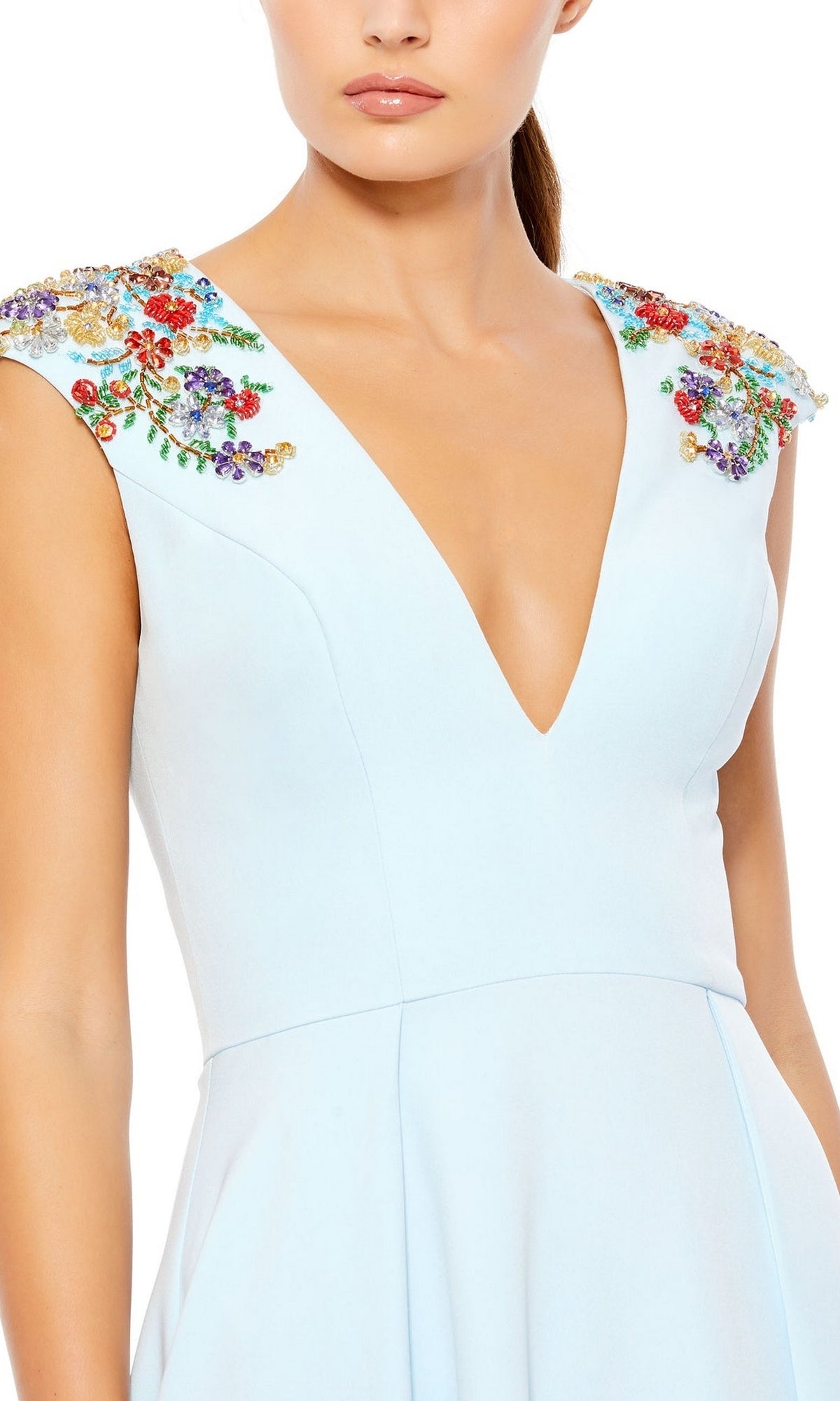 A woman wearing the Cap-Sleeve Long Formal Dress: Mac Duggal 26540, a light blue gown featuring a deep v-neck and colorful floral embellishments on the shoulders.