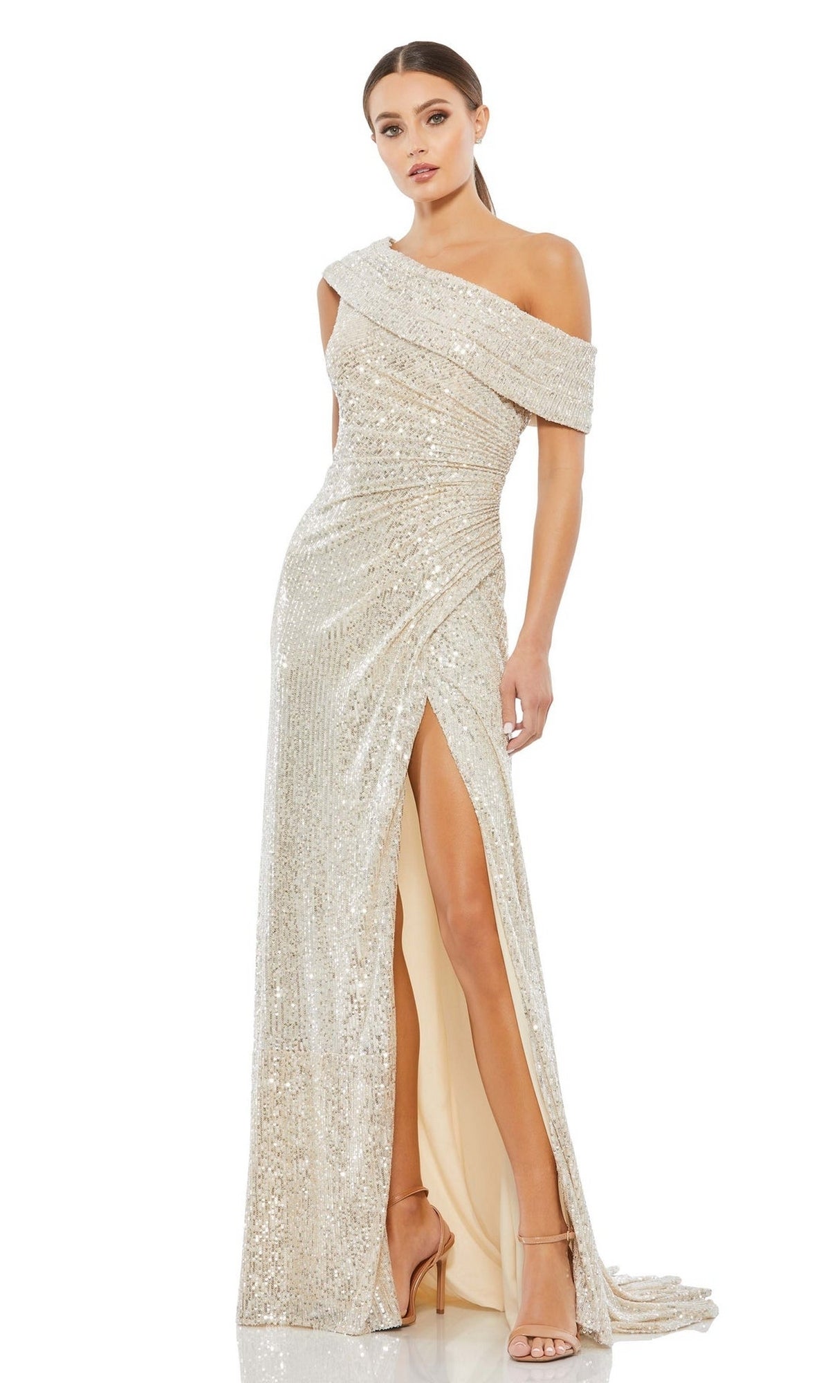 A woman poses against a plain background wearing the Mac Duggal 26550 Drop-Shoulder Sequin Formal Gown—a floor-length, high-slit dress—paired with strappy high-heeled sandals.