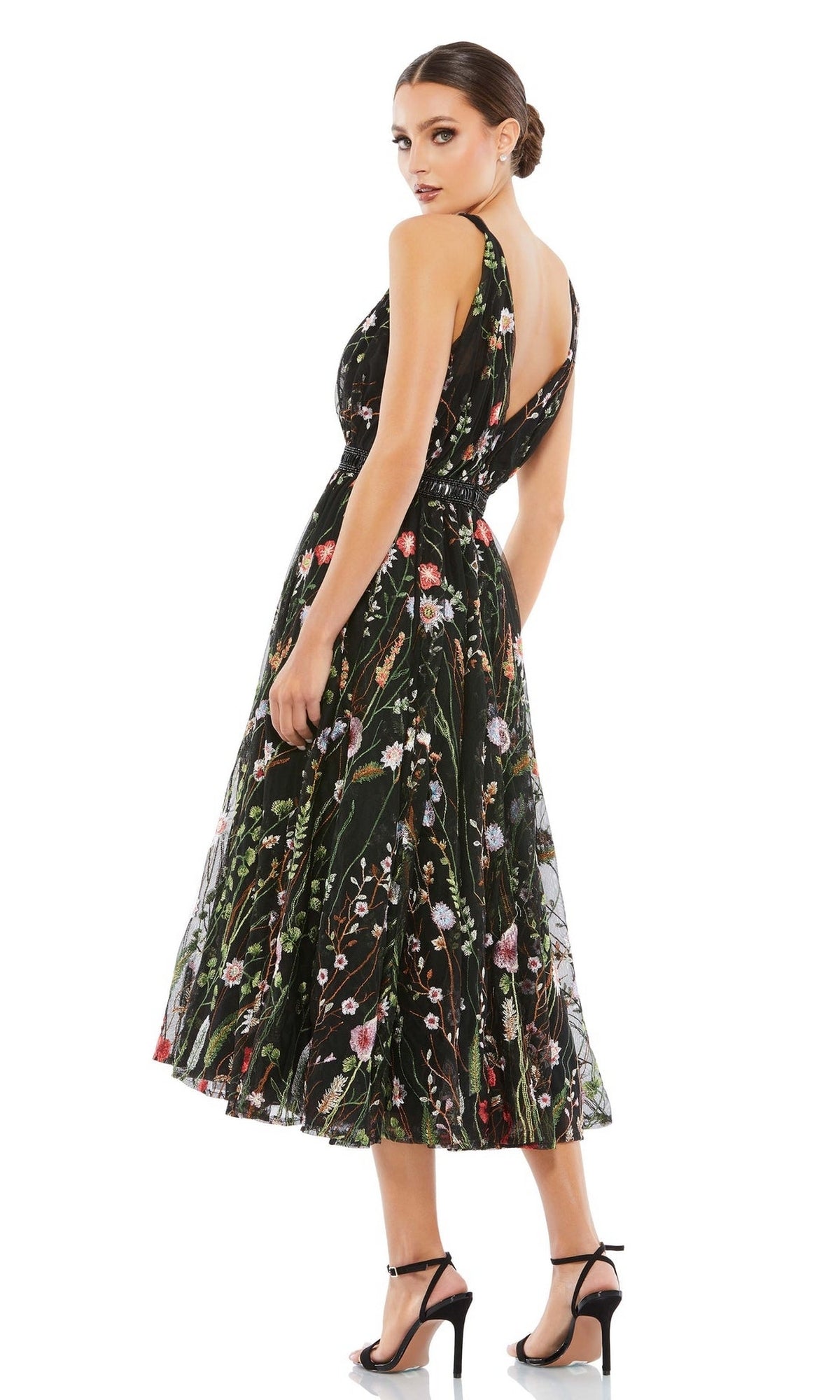 Woman modeling the Mac Duggal 26557 Black Floral Wedding Guest Dress, a black sleeveless midi with floral embroidery and open back, styled with black heels—perfect for parties or weddings—on a white background.