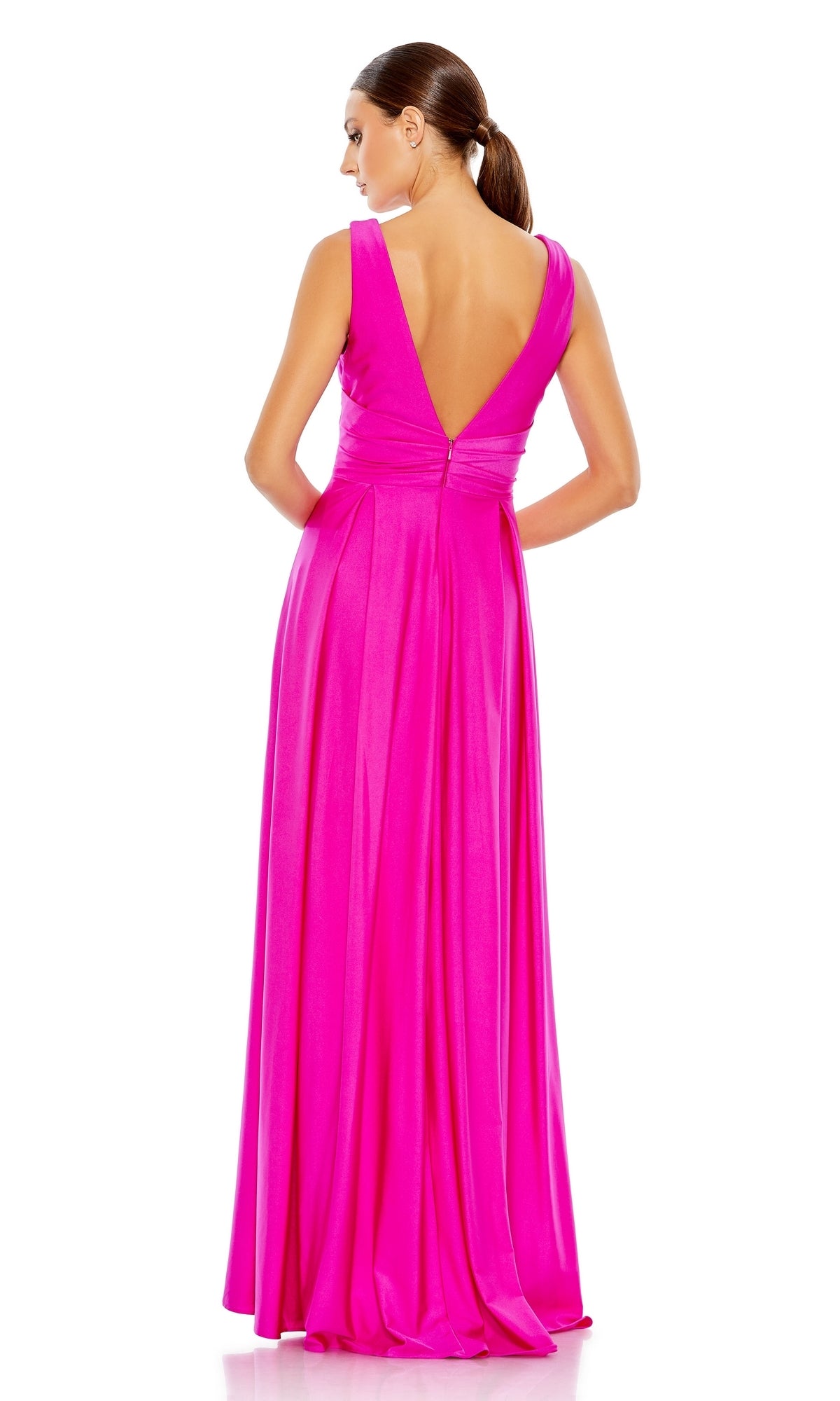 A woman with a low ponytail stands facing away against a white background, wearing the Mac Duggal 26578: a vibrant pink V-neck long A-line prom dress with a deep V-back.