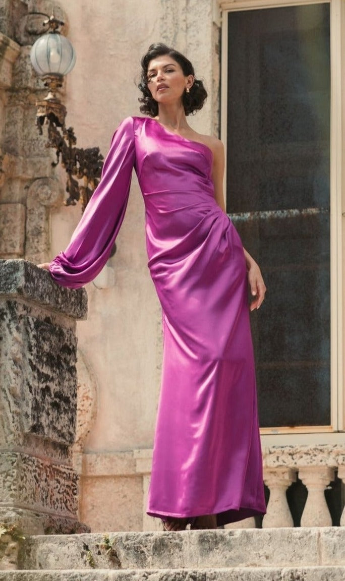 A woman in a shiny fuchsia Mac Duggal 26588 one-sleeve long formal dress stands on stone steps before an old building.