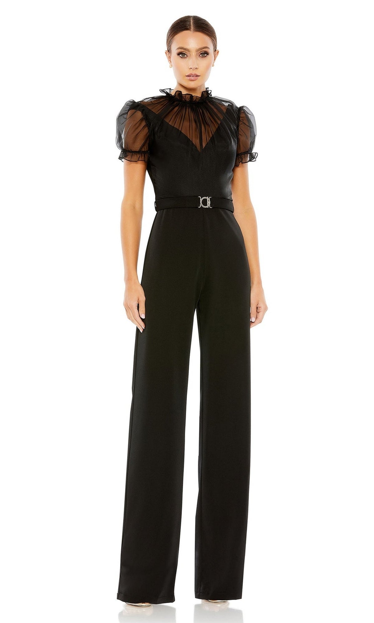 A woman stands against a white background wearing the Long Formal Jumpsuit 26621 by Mac Duggal, featuring sheer puff sleeves, a belted waist, and wide-leg pants.