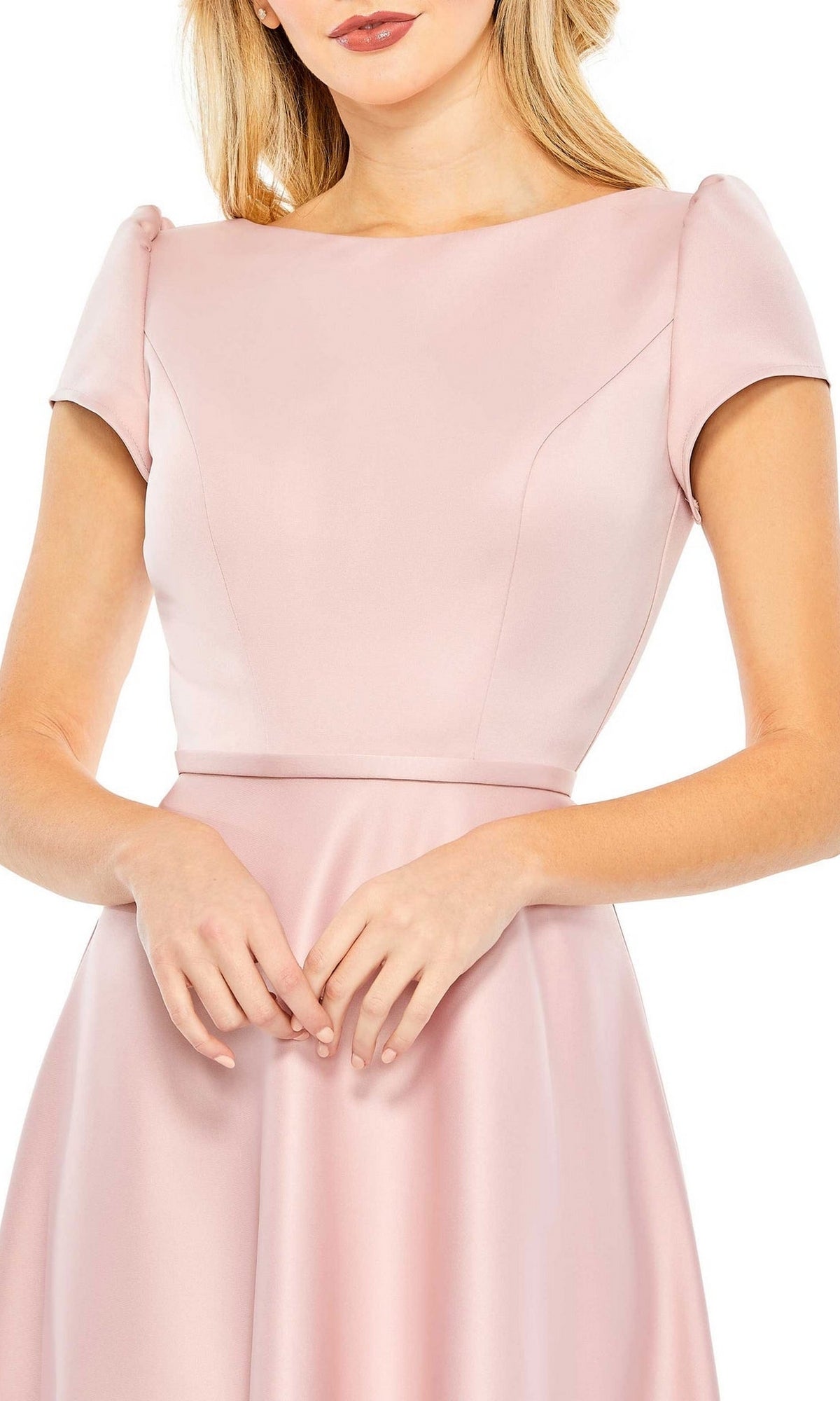 A woman wears the Short Wedding Guest Dress 26663 by Mac Duggal—a light pink, satin, short-sleeve dress with a fitted bodice and flared skirt—standing against a plain white background.