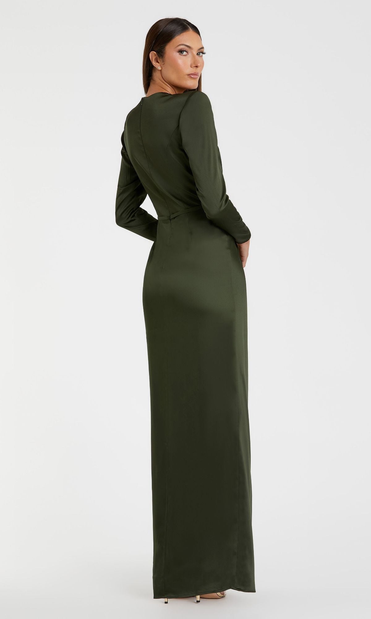 A woman models the Mac Duggal 26676 Bold-Shoulder Long Formal Dress, a bra-friendly, floor-length dark green gown, standing with her back turned and head to the side against a plain white background.