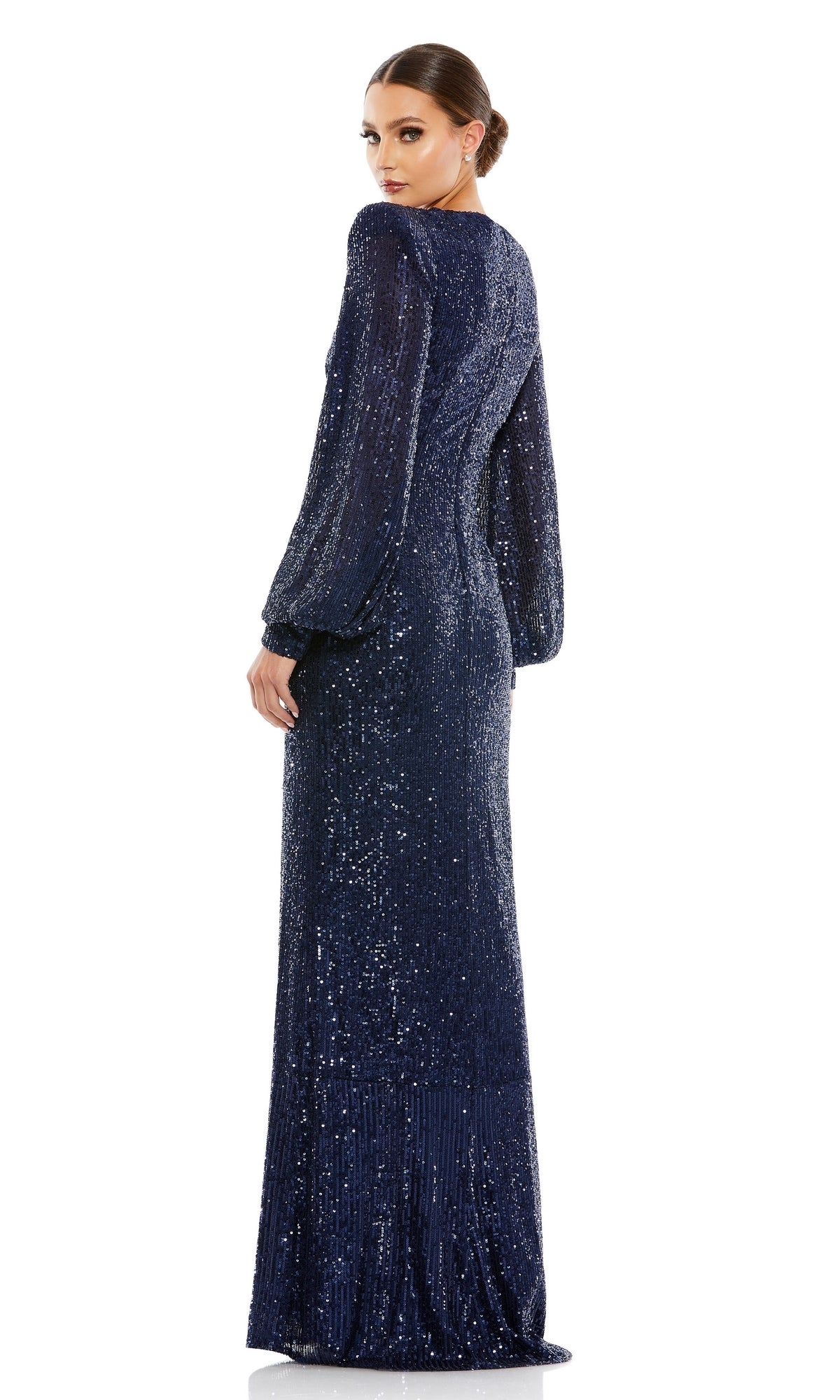 A woman stands facing away, wearing Mac Duggal's Long Formal Dress 26722—a long-sleeved, floor-length navy blue sequin gown with an elegant v-neckline.