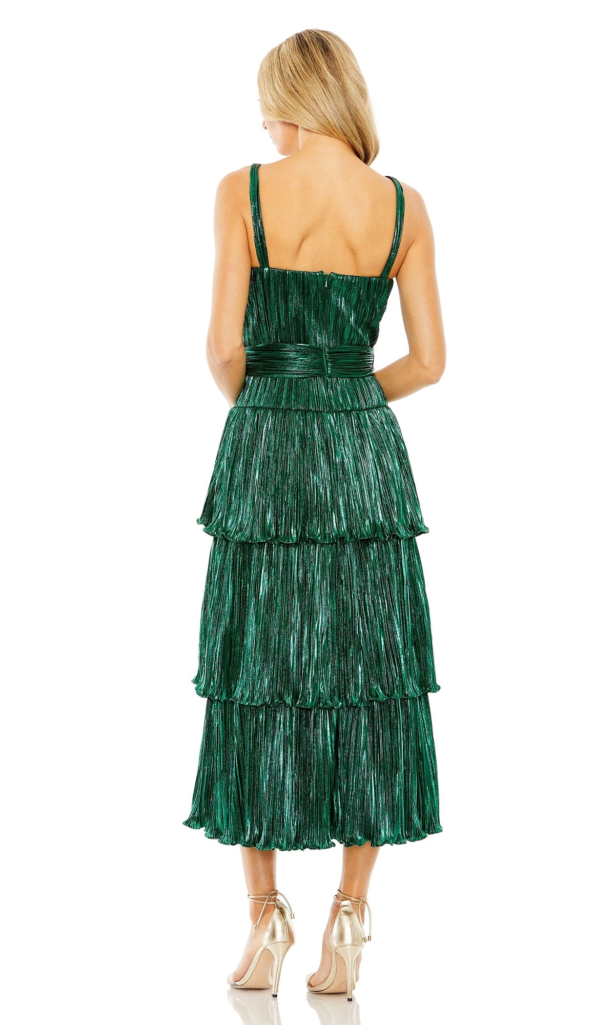 A woman faces away, wearing the Mac Duggal Tea-Length Metallic Party Dress 27062—a sleeveless, tiered green dress with a fitted waist—paired with gold high-heeled shoes.