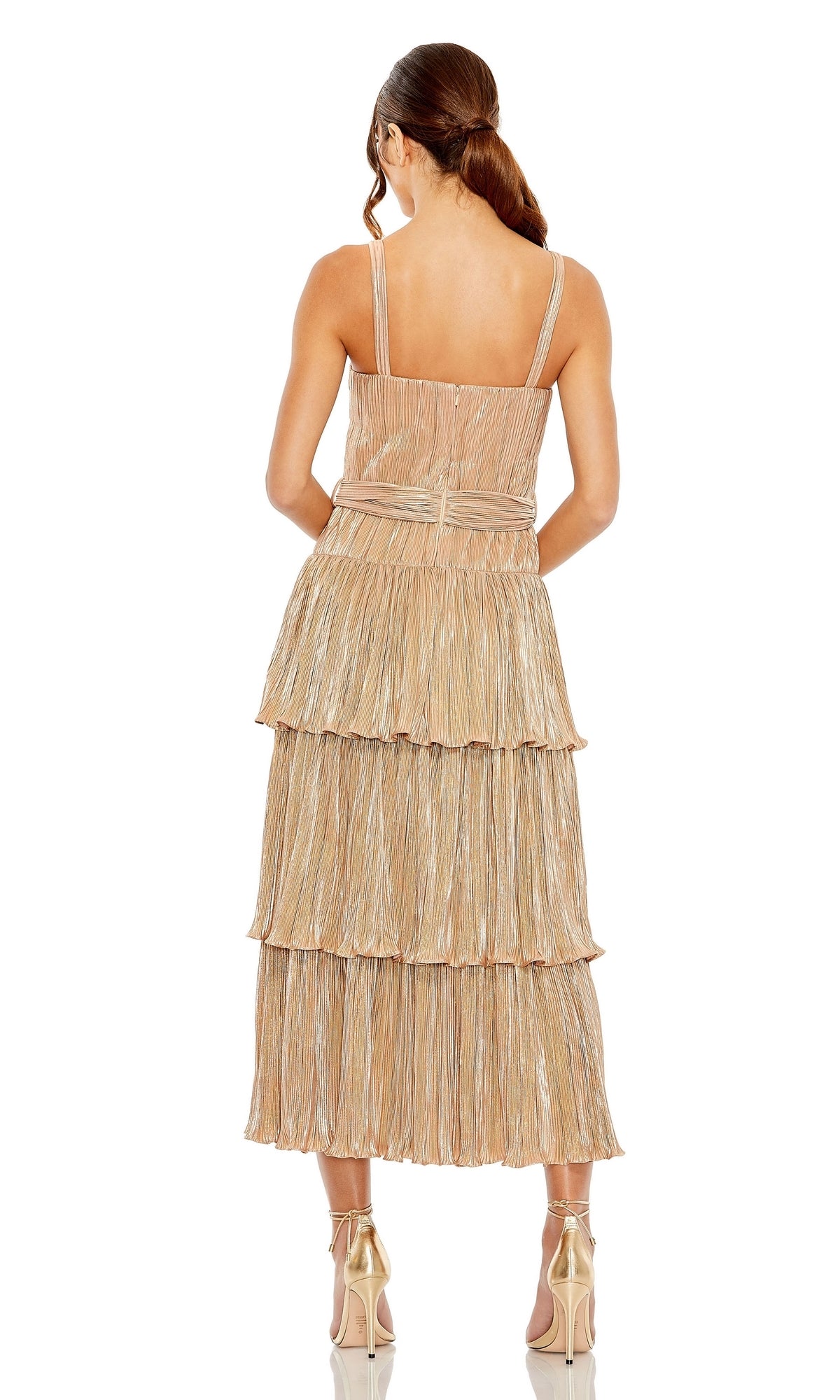 A woman stands with her back to the camera, wearing the Mac Duggal Tea-Length Metallic Party Dress 27062 with thin straps and pleated tiers. Her low ponytail pairs perfectly with metallic high-heeled shoes.