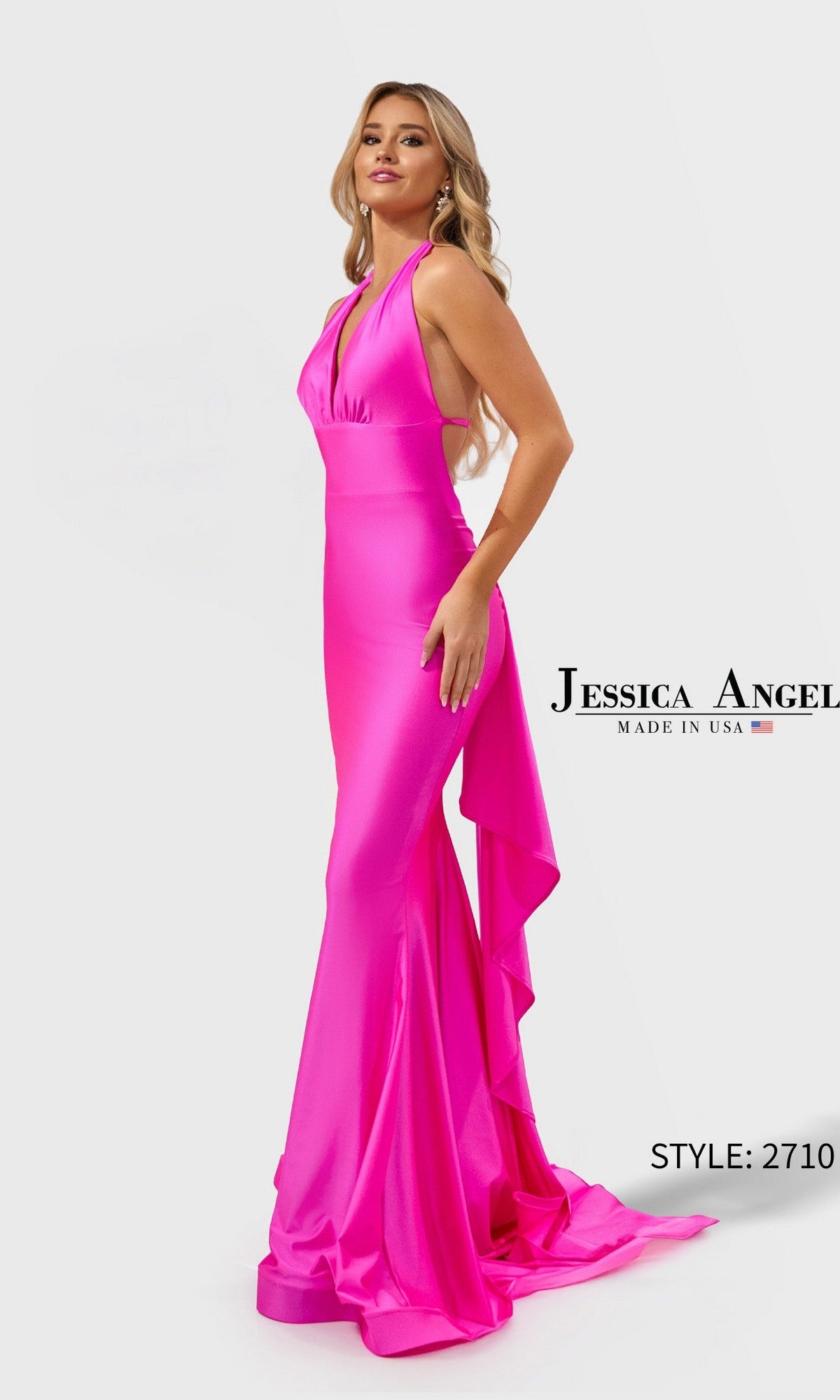 A woman stands against a plain light background in the Jessica Angel 2710 long prom dress, featuring a fuchsia halter neckline, fitted mermaid silhouette, and a cascading ruffle at the back.