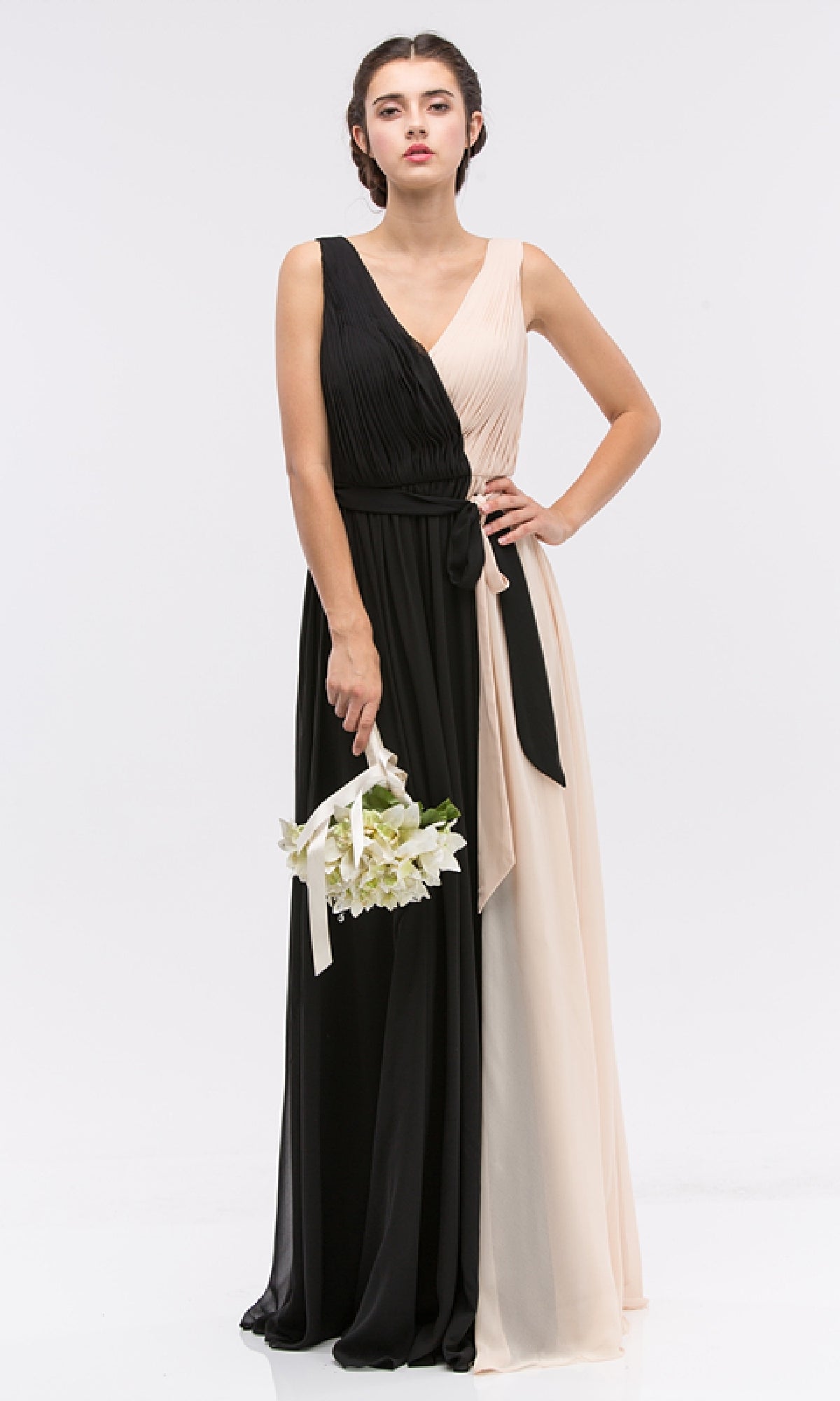 A woman holds a small bouquet while wearing the Eureka 2711, a sleeveless, floor-length two-toned black and beige chiffon formal dress with a V-neck and tied waist.