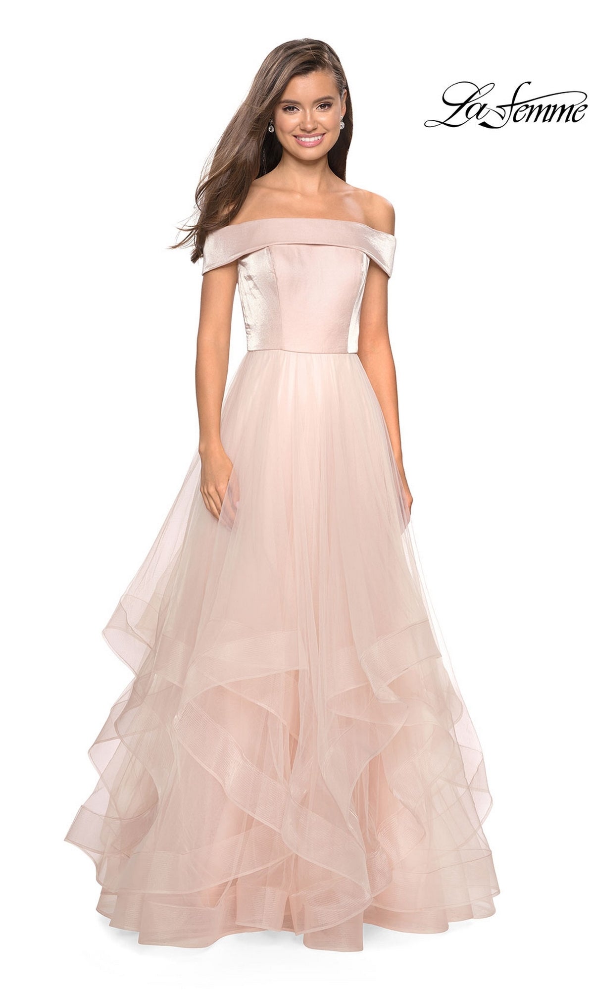 A woman wears the La Femme Off-Shoulder Long Tiered Prom Dress 27224 in blush pink, featuring a fitted bodice and ball gown skirt. The