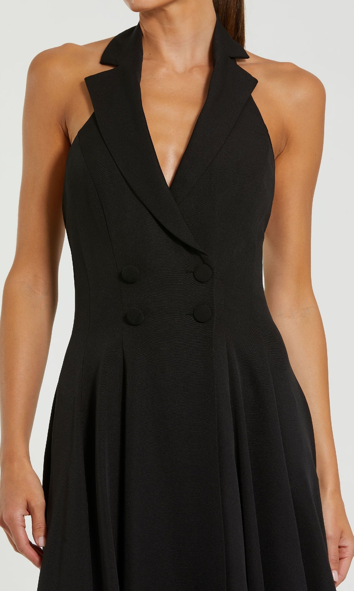A woman wearing the Mac Duggal 27252 Blazer Halter Midi Party Dress—a sleeveless black dress with a deep V-neck, wide lapels, and double-breasted button details.