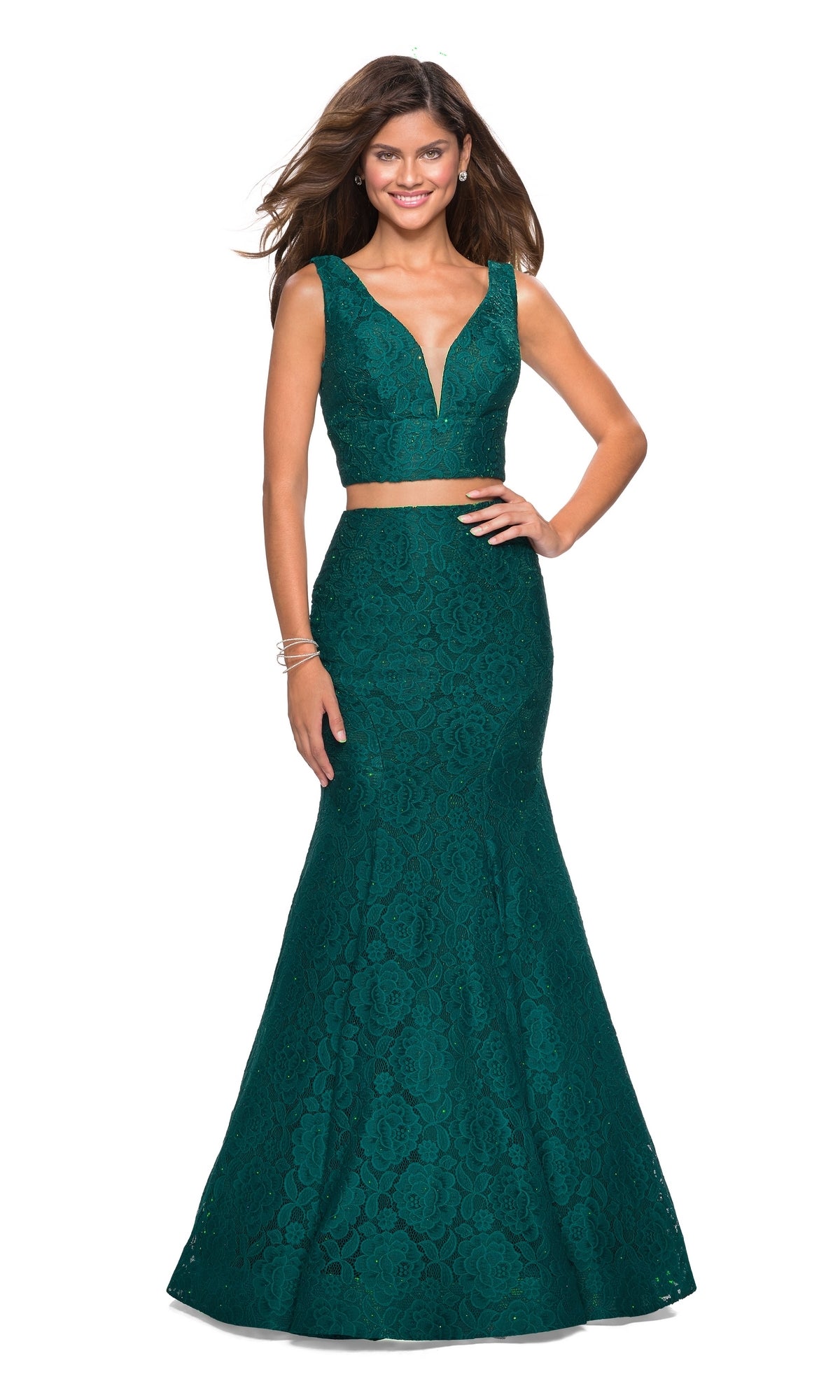 Woman wearing the La Femme Two-Piece Mermaid Lace Prom Dress 27262 in forest green, featuring a sleeveless, deep V-neck design and fitted mermaid silhouette, standing with a smile and one hand on her hip.