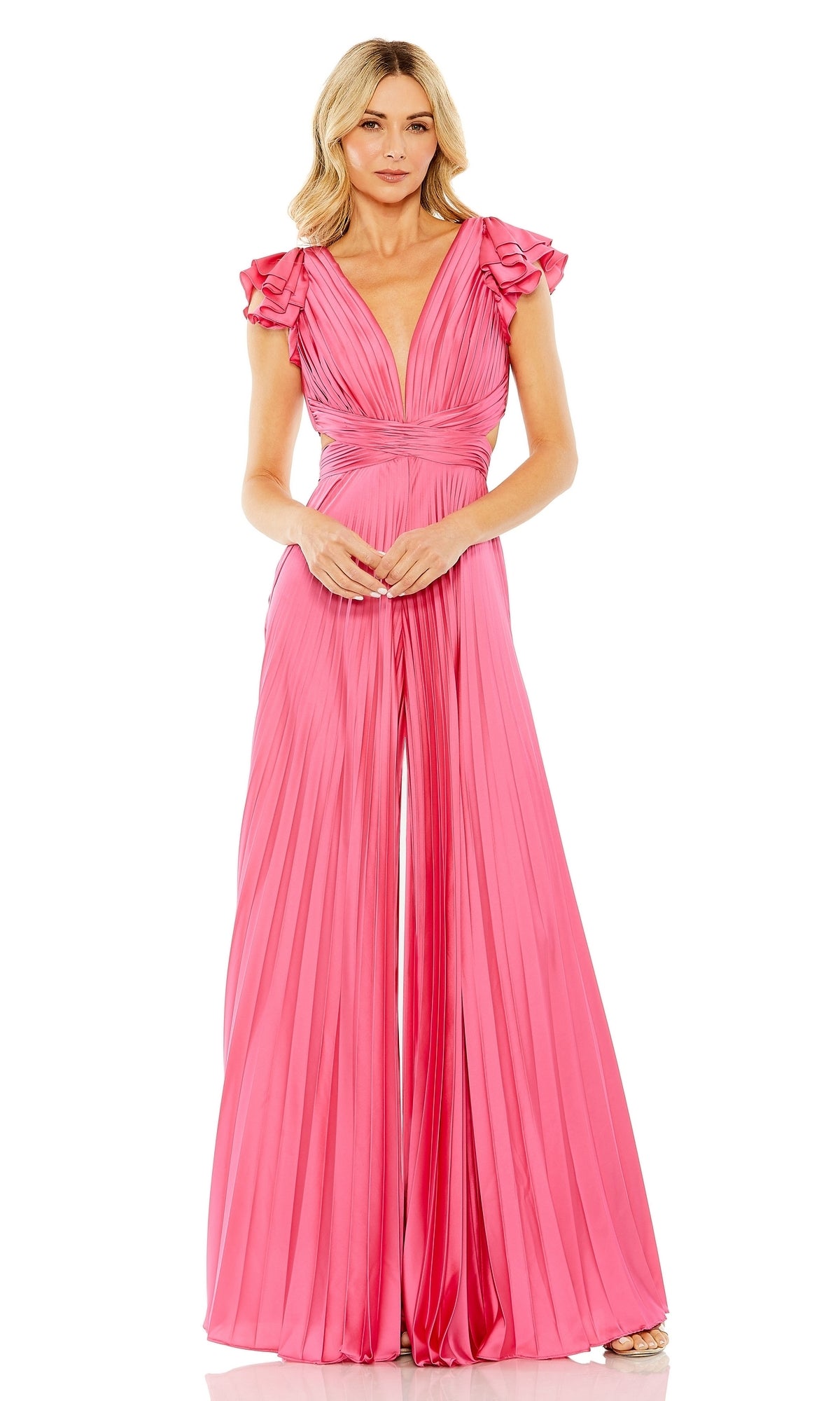 A woman stands wearing the Pleated Formal Jumpsuit 27361 by Mac Duggal, featuring bright pink pleats, ruffled cap sleeves, a deep V-neckline, fitted waist, and a delicate lace-up back.