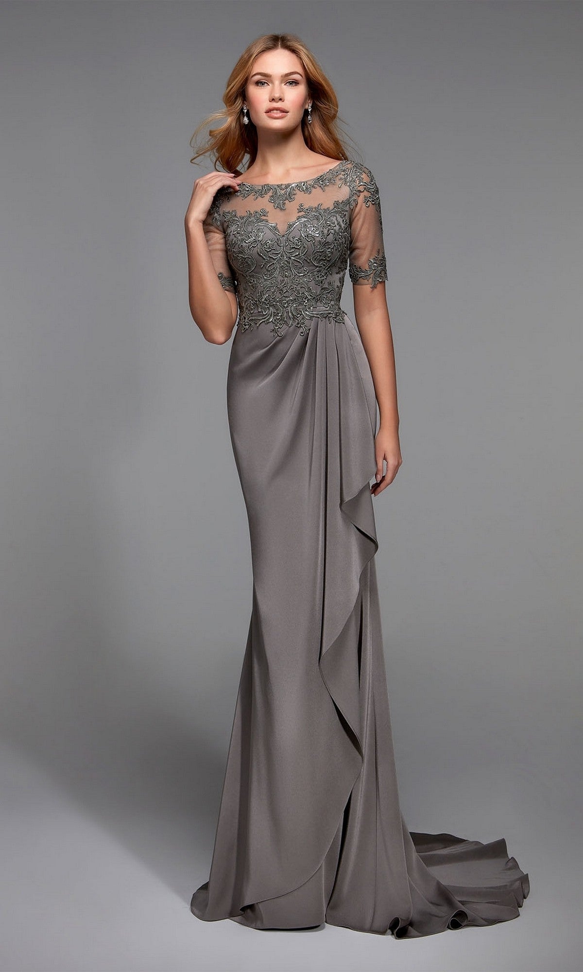A woman wears the Alyce 27477 long formal dress in Stone, featuring an embellished bodice, lace details, and sheer short sleeves, standing against a plain gray background.
