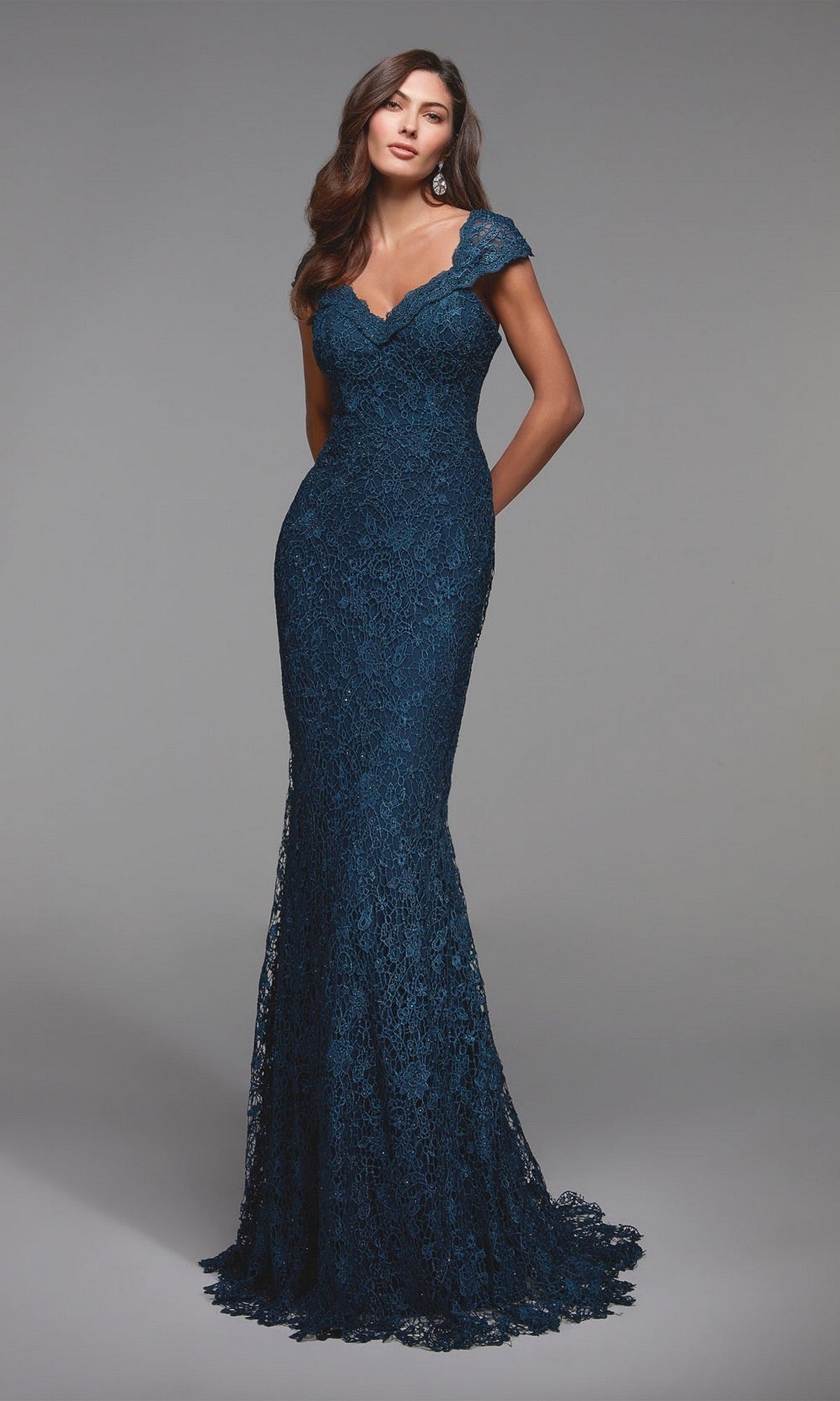 A woman in the Alyce 27496 long formal dress in Blue Opal, featuring a fitted mermaid silhouette with shimmering lace and cap sleeves, stands against a plain gray background.