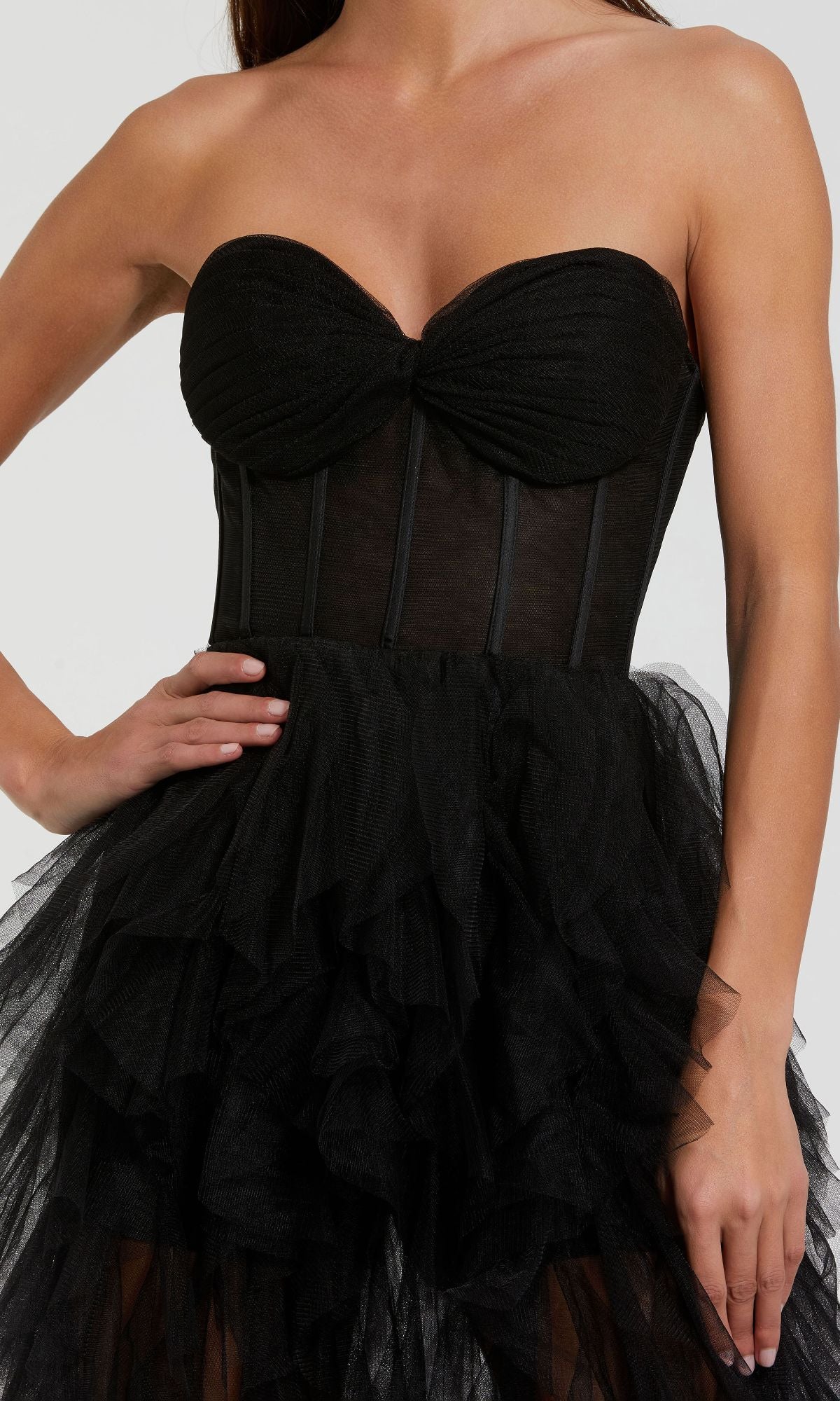 Woman wearing the Mac Duggal 27532 Strapless Ruffled Long Prom Dress, featuring a fitted bodice and layered tulle skirt, poses with one hand on her hip.