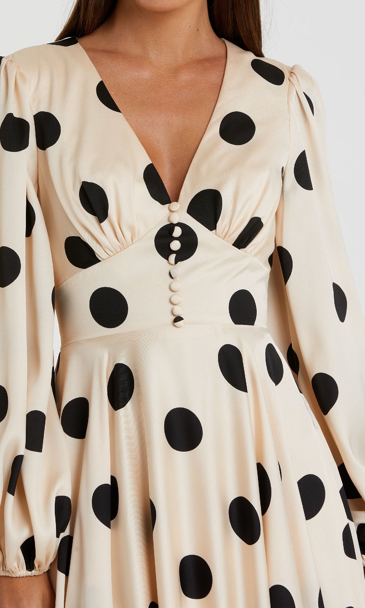 Close-up of the Mac Duggal 27542 Midi Polka-Dot Semi-Formal Dress—cream with black spots, long puffed sleeves, deep V-neck, fabric-covered buttons, and fitted waist—ideal as a vintage-inspired party dress for semi-formal events.