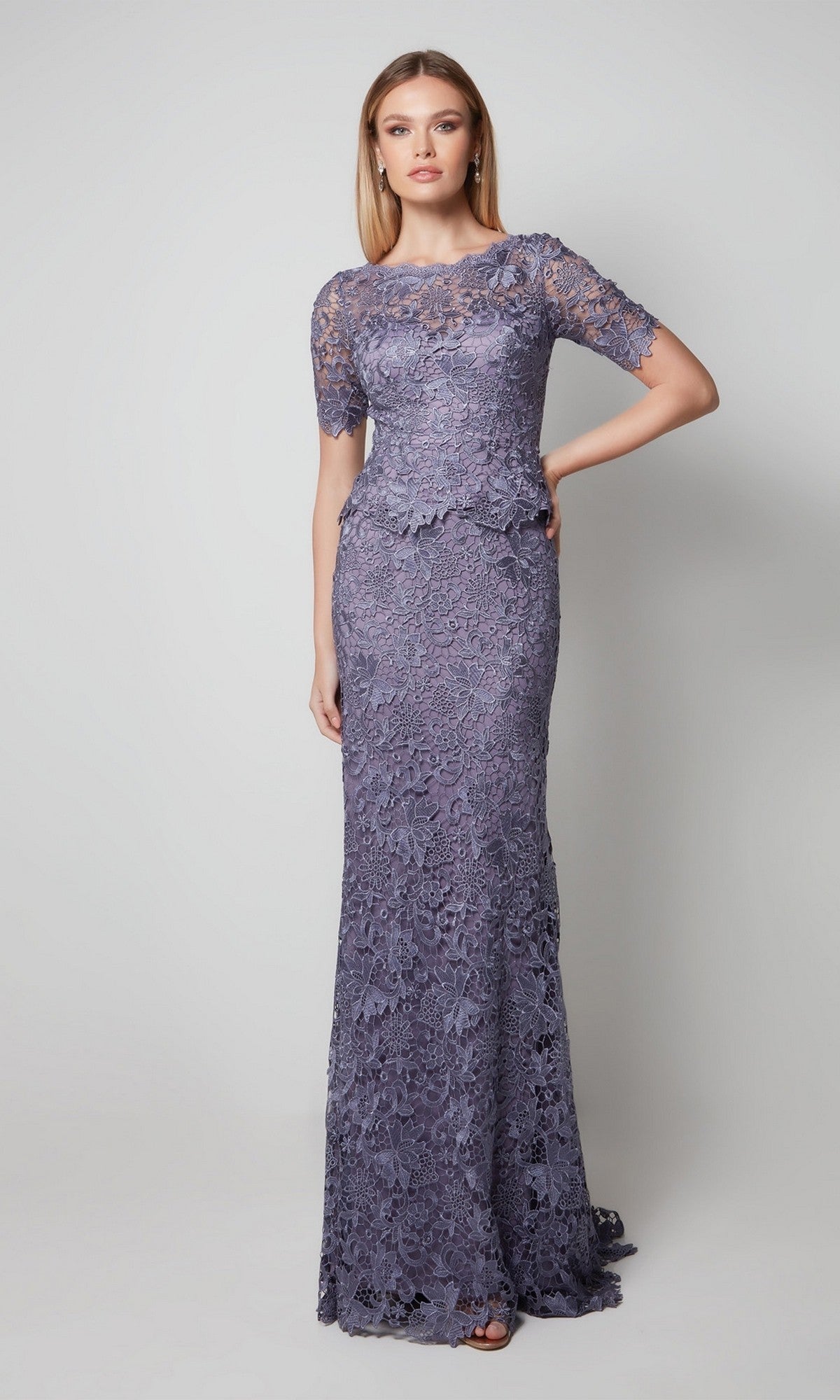 A woman models the Alyce 27555, a floor-length lavender lace formal dress with short sleeves and a fitted silhouette, ideal for mother-of-the-bride attire, against a plain light background.