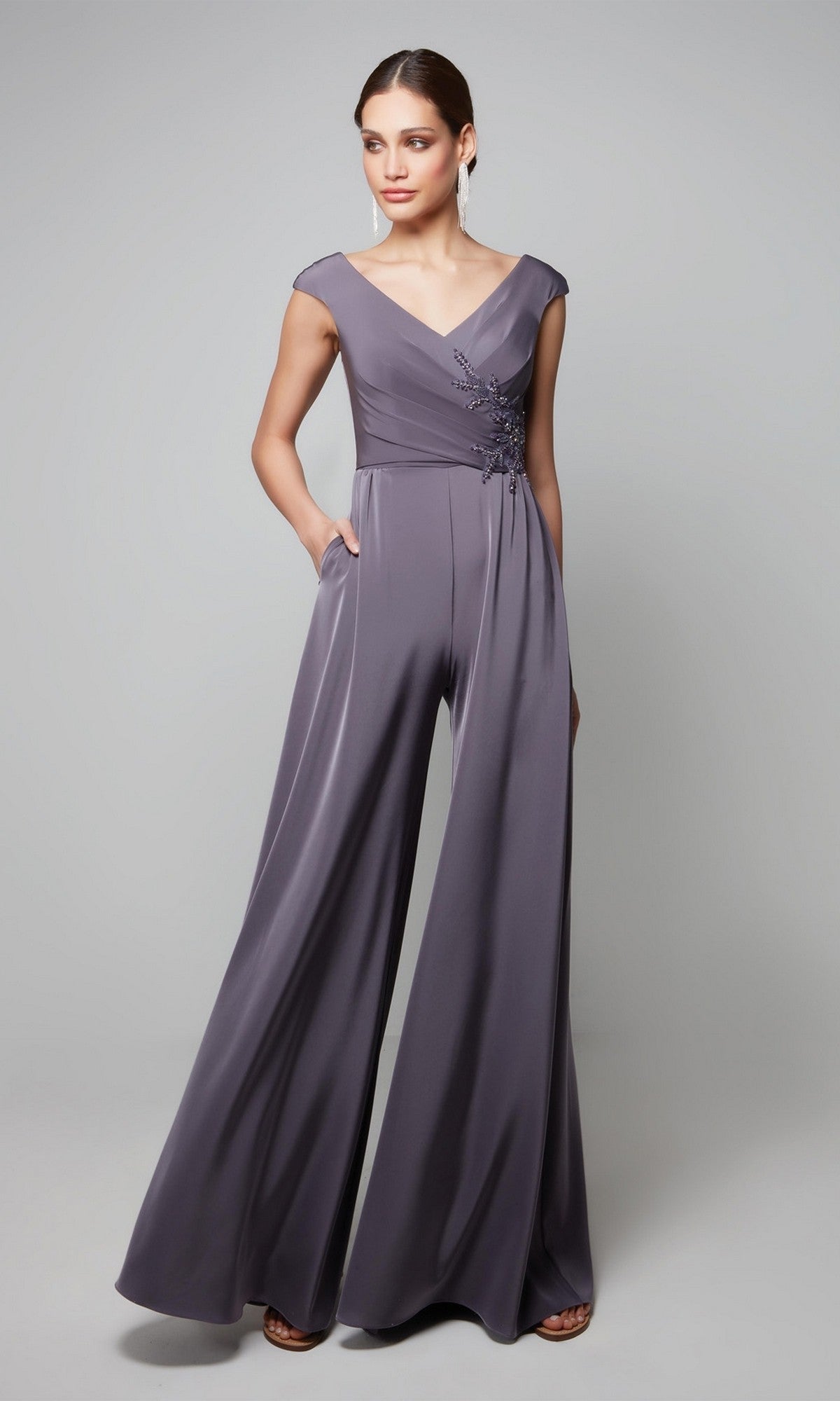 A woman models the Alyce 27559 Long Formal Jumpsuit—a sleeveless, wide-leg mauve piece with a V-neckline and floral bodice details—perfect for wedding guests, set against a plain background.