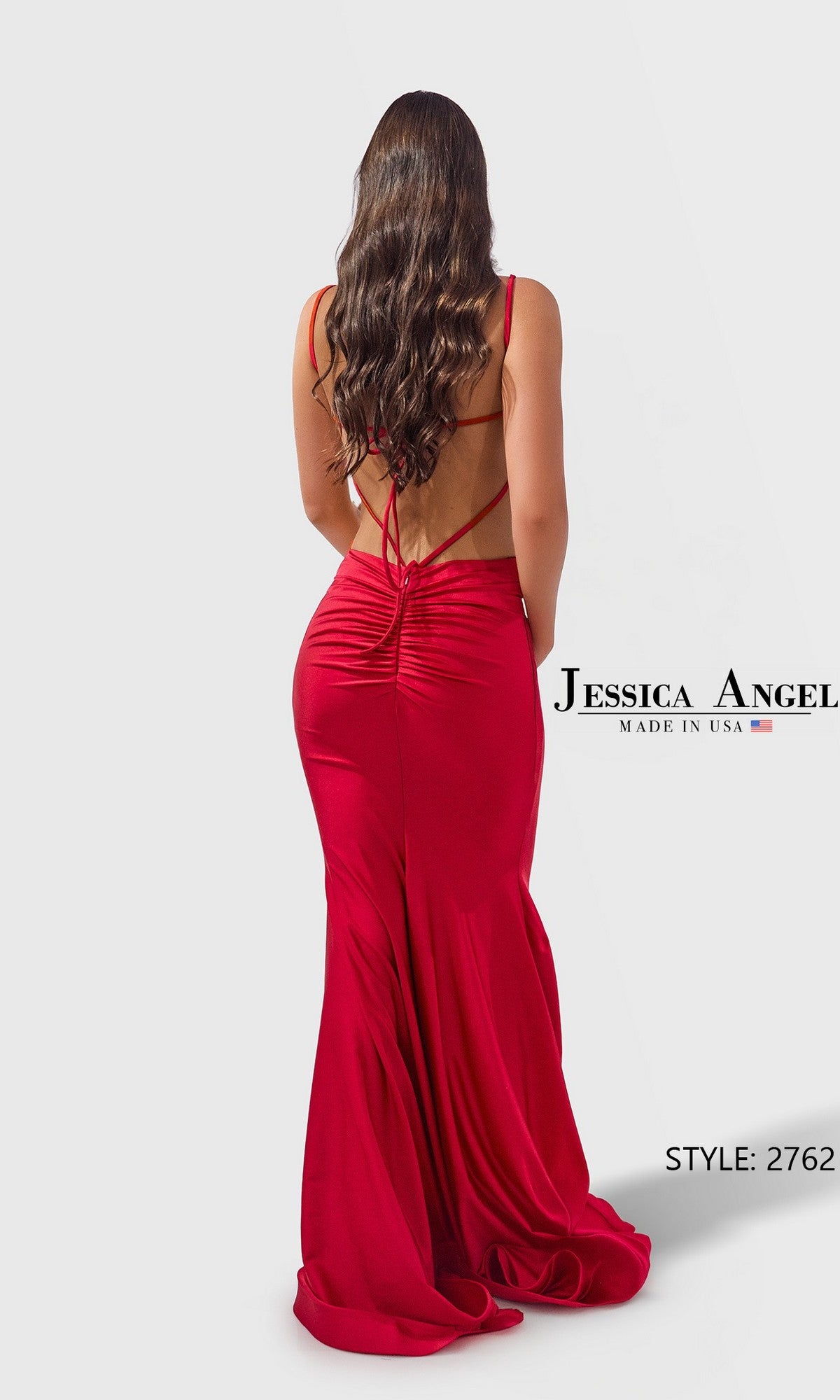 A woman with long wavy hair wears the fitted, floor-length Jessica Angel 2762 prom dress with thin straps. Text: