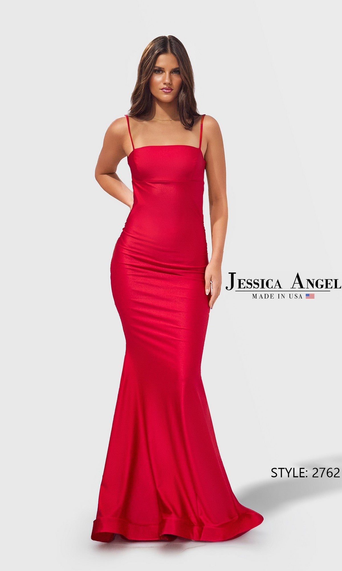 A woman in a fitted, floor-length red Jessica Angel 2762 prom dress with thin straps stands against a plain light background. Text reads