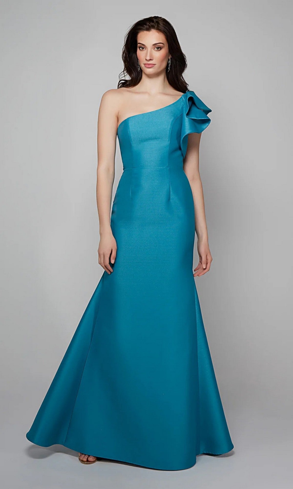 Woman models the Alyce 27641 long formal dress—a teal, floor-length, one-shoulder gown with ruffle shoulder detail—against a plain gray background.