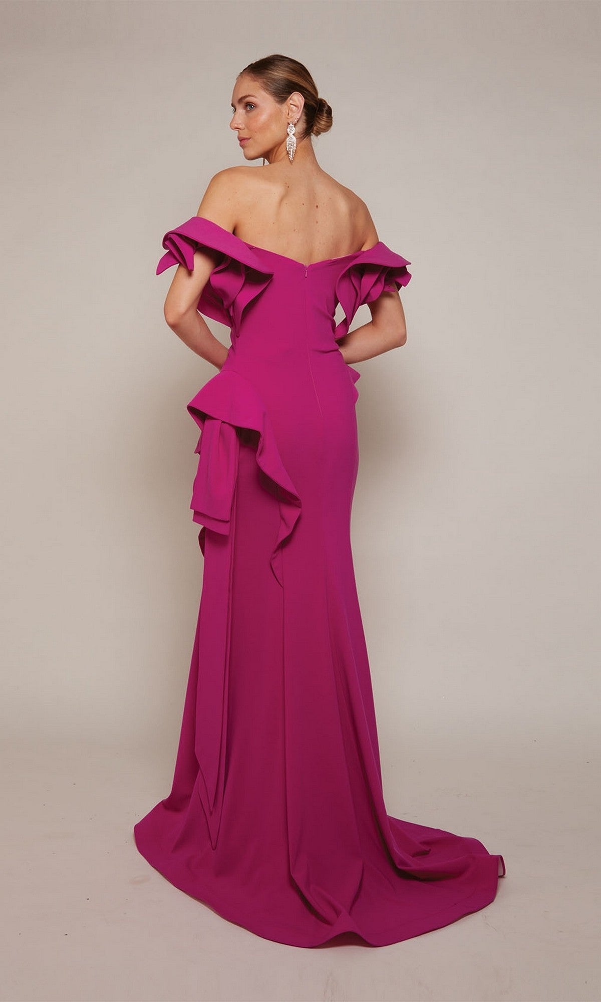 A woman faces away from the camera in the Alyce 27643, a magenta, floor-length formal gown with off-the-shoulder ruffled sleeves and a side drape—an elegant choice for mothers of the bride.