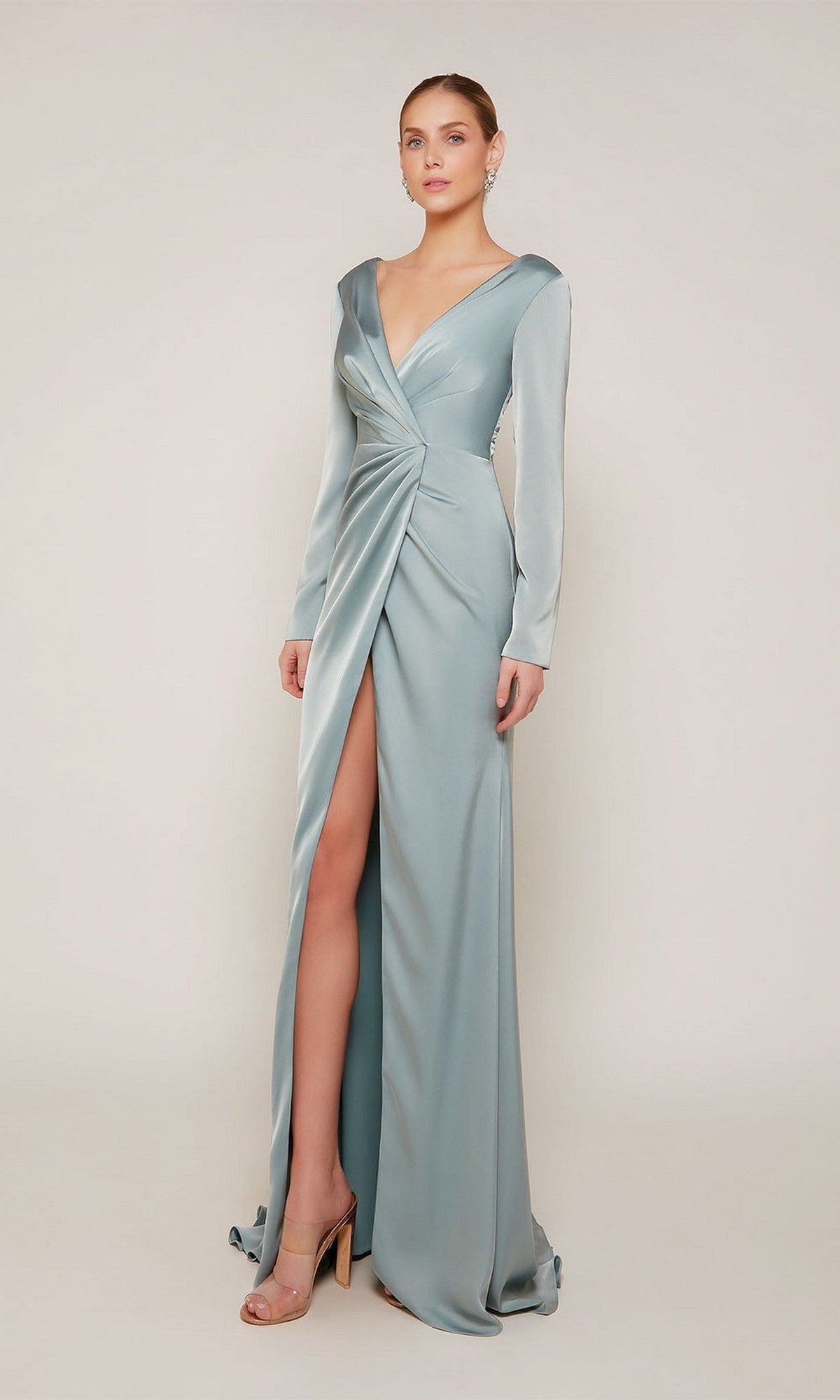 A woman wears the Alyce 27694, a long formal sage green satin dress with long sleeves, a deep V-neckline, and a high front slit—an elegant mother-of-the-bride choice against a plain background.