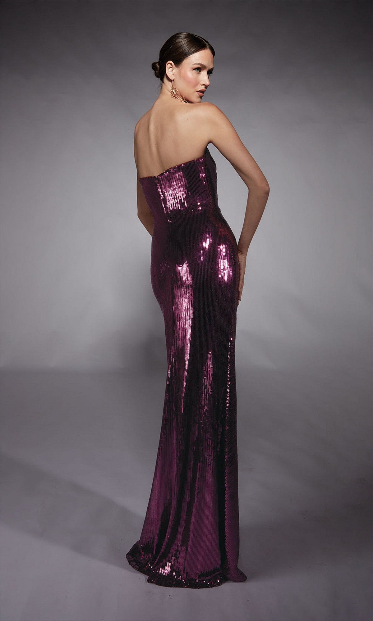 A woman in the Alyce 27704 long formal dress stands facing away, looking over her shoulder against a neutral background.